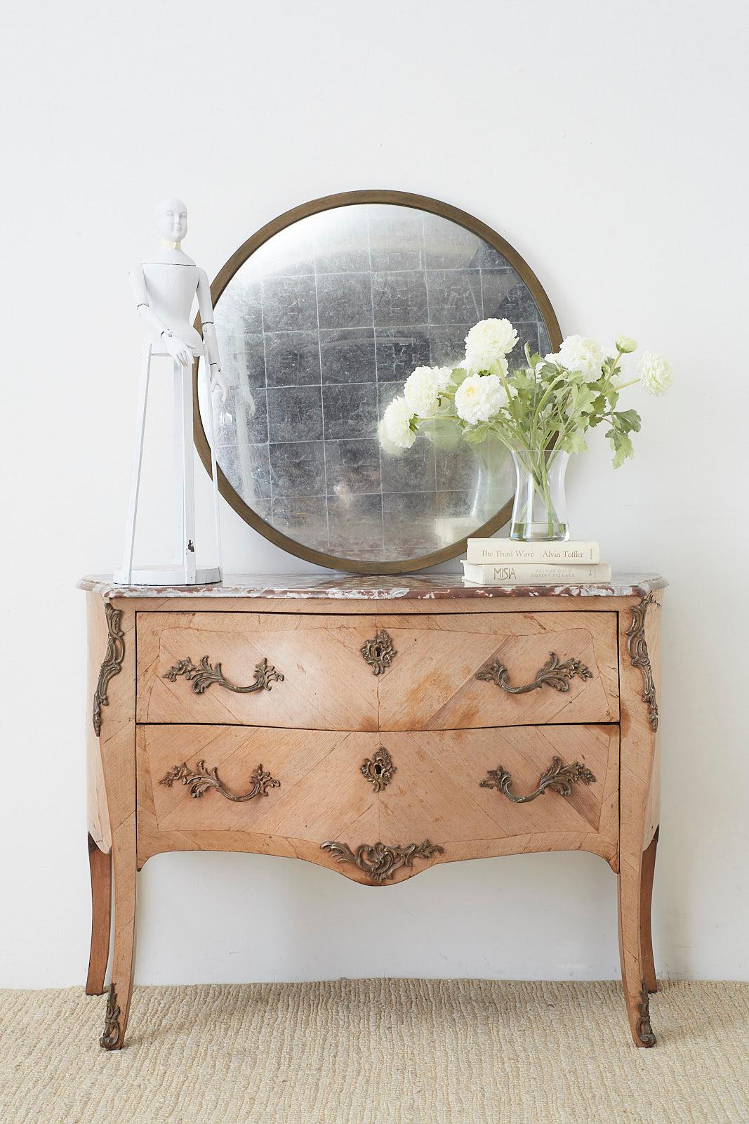 Beautifully faded French bombe chest, dresser, or commode featuring a variegated marble top. Made in the Louis XV taste and embellished with bronze mounts and pulls. The chest has a faded patina on the veneered surfaces showcasing the lovely grain