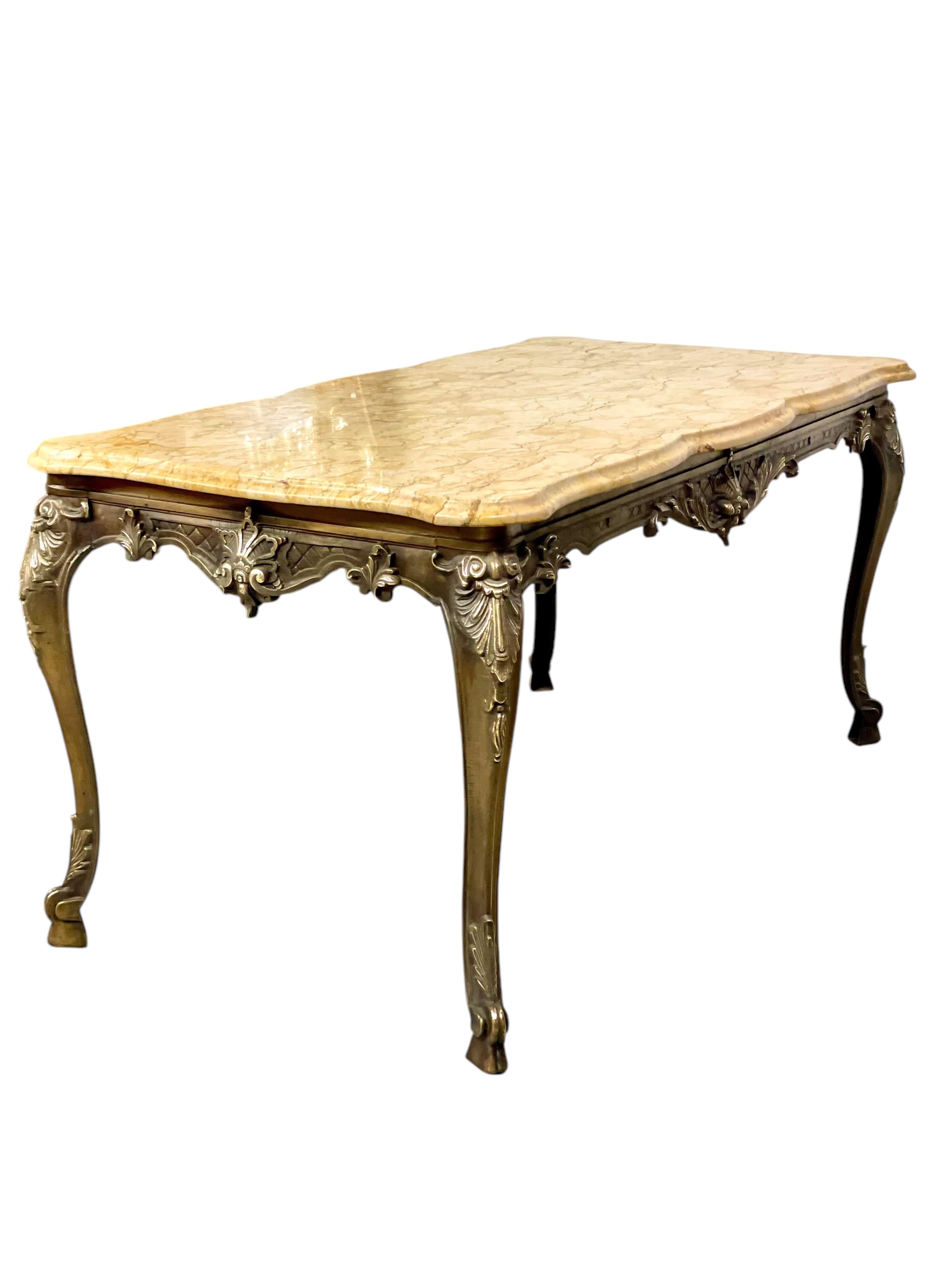 This elegant mid-20th century coffee table embodies the refined craftsmanship and timeless aesthetics of the Louis XV style. Featuring a luxurious marble top with warm beige tones and subtle veining, the table’s surface boasts a curvaceous
