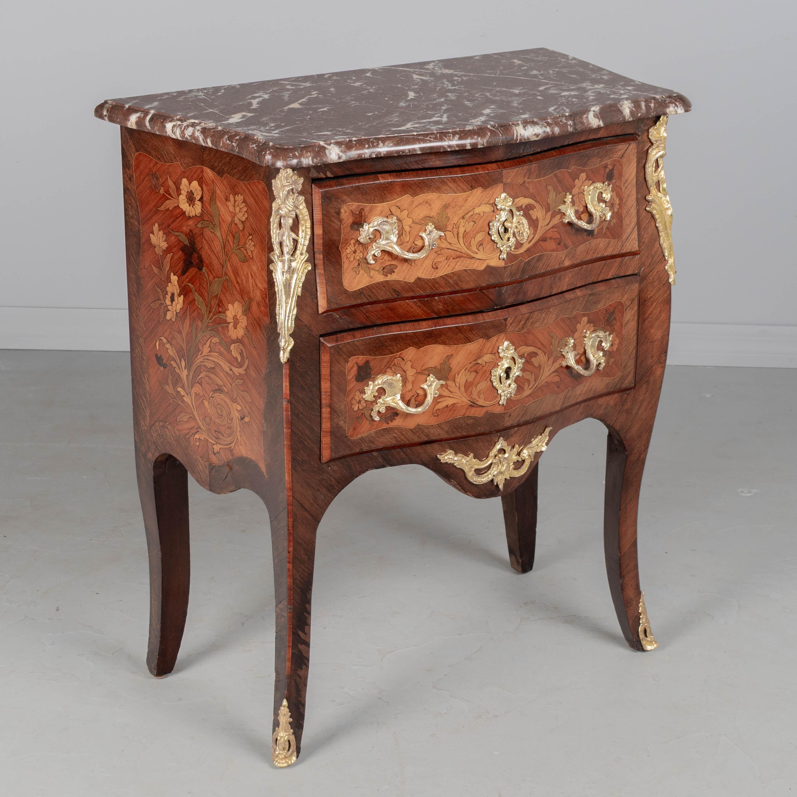 Commodo francese in stile Luigi XV con piano in marmo intarsiato e montato in bronzo, finemente realizzato in mogano massiccio con impiallacciature intarsiate di noce, mogano e vari Wood esotici. Bellissimo disegno a intarsio floreale sui lati.