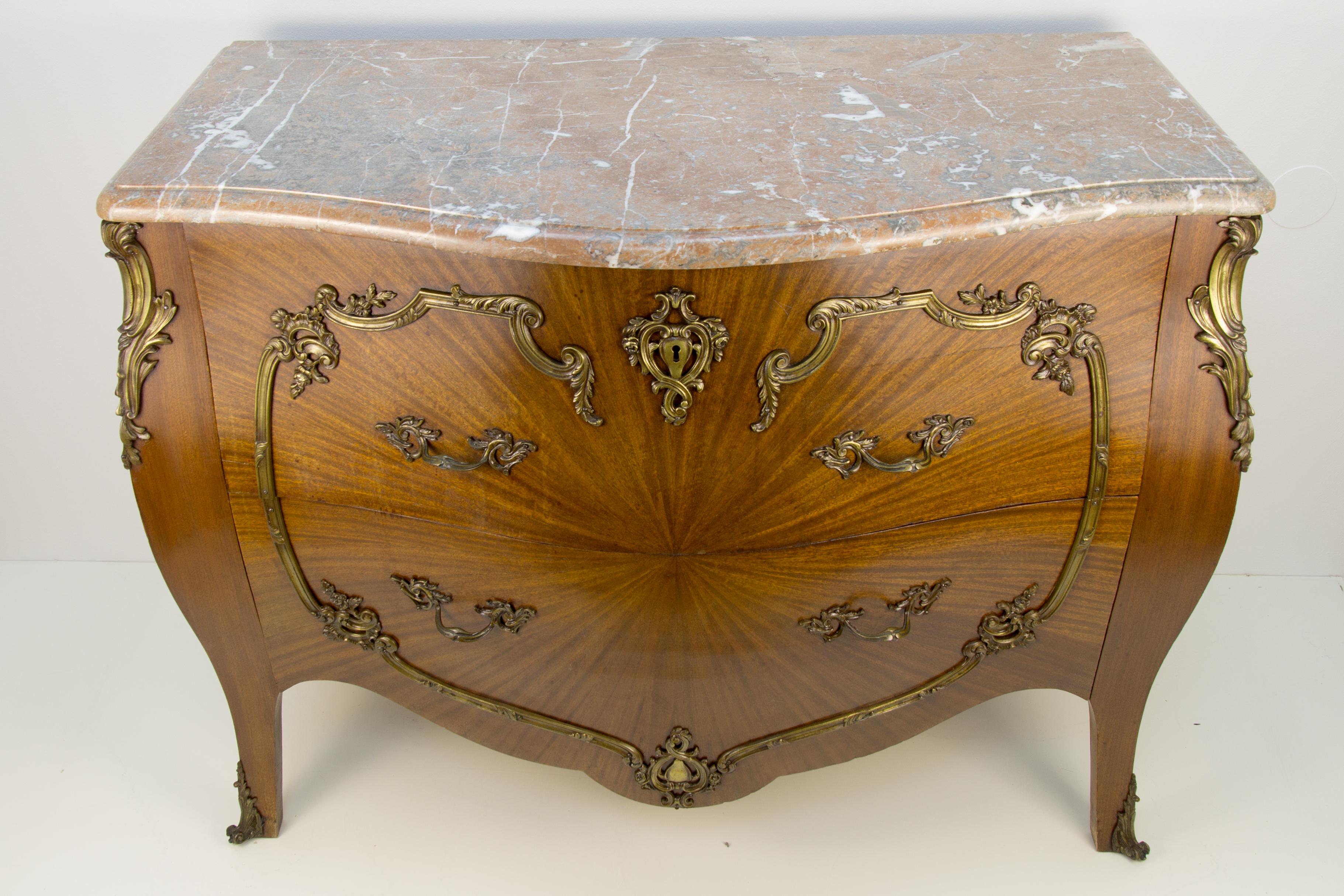 An elegant and beautifully shaped French Louis XV style bombée commode. The chest of drawers has a marble top in grey, brown, and white tones with molded edge, a bombée body with two deep drawers, and bronze scrolling mounts.
Dimensions: height 88