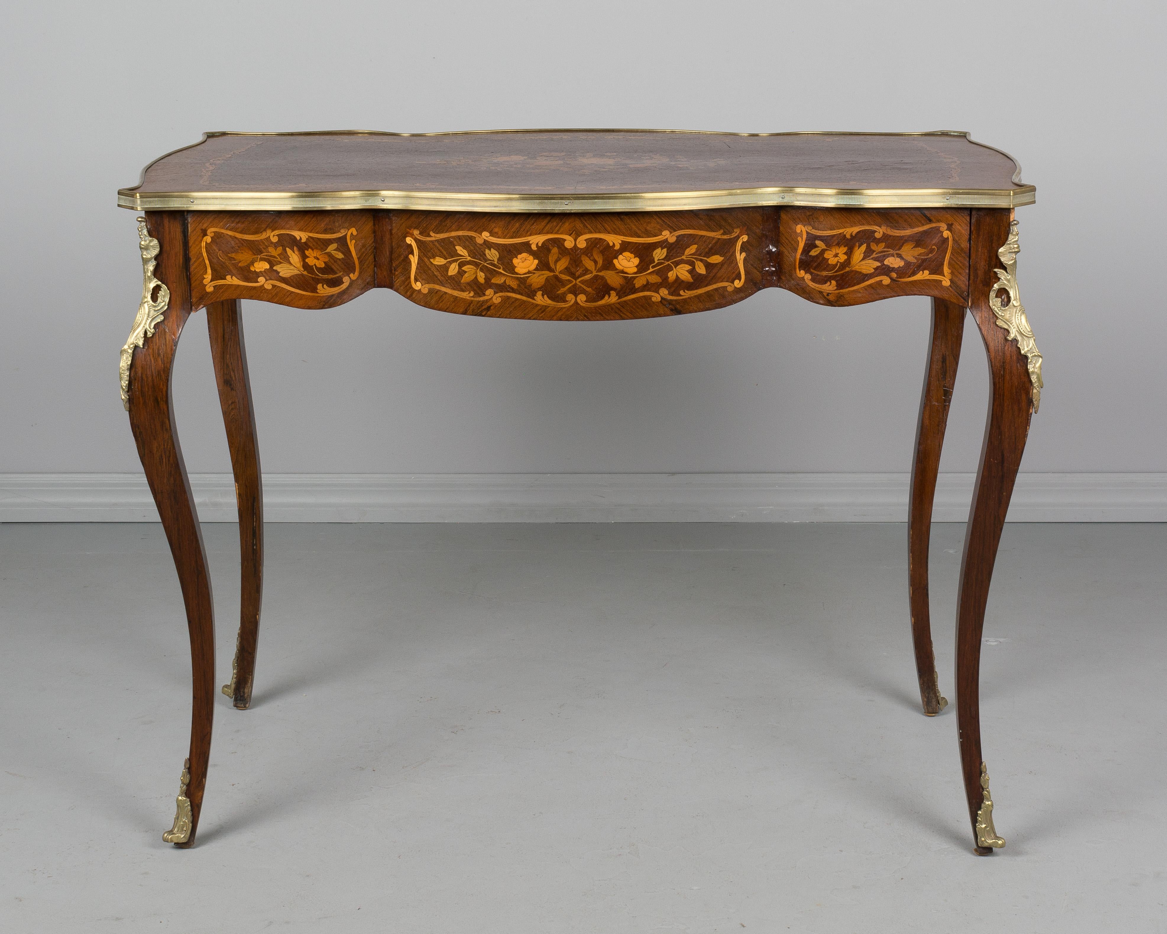 An early 20th century Louis XV style marquetry, bronze-mounted desk with a large dovetailed drawer. Finished on all four sides with fine floral motif inlay of mahogany. Elegant slender curved legs with bronze corner decorations and sabots. French