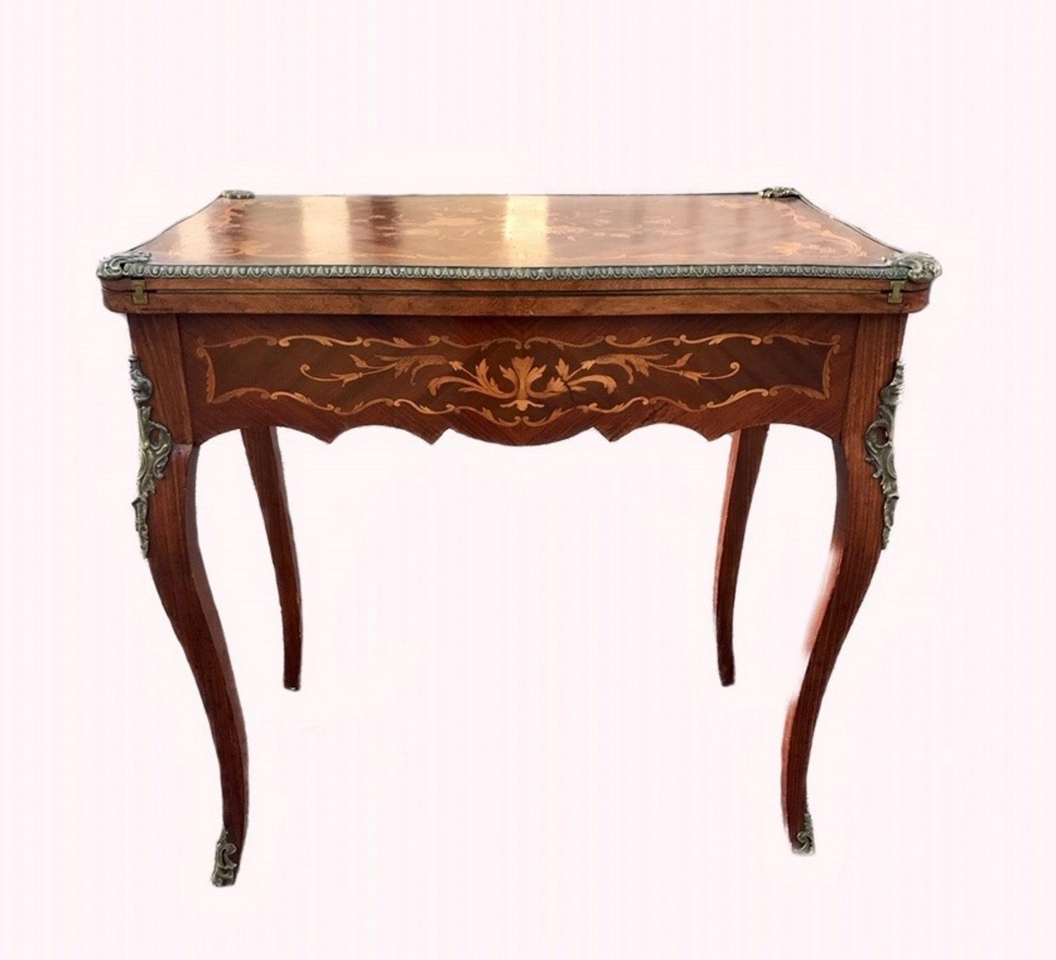 Dieser wunderbare Spieltisch aus dem späten 19. Jahrhundert in Mahagoni-Furnier ist exquisit
mit floralen Intarsien aus Königsholz und Satinholz auf allen Seiten eingelegt. Er hat Bronzebeschläge und Cabriole-Beine:: die in Bronzefüßen enden. Der