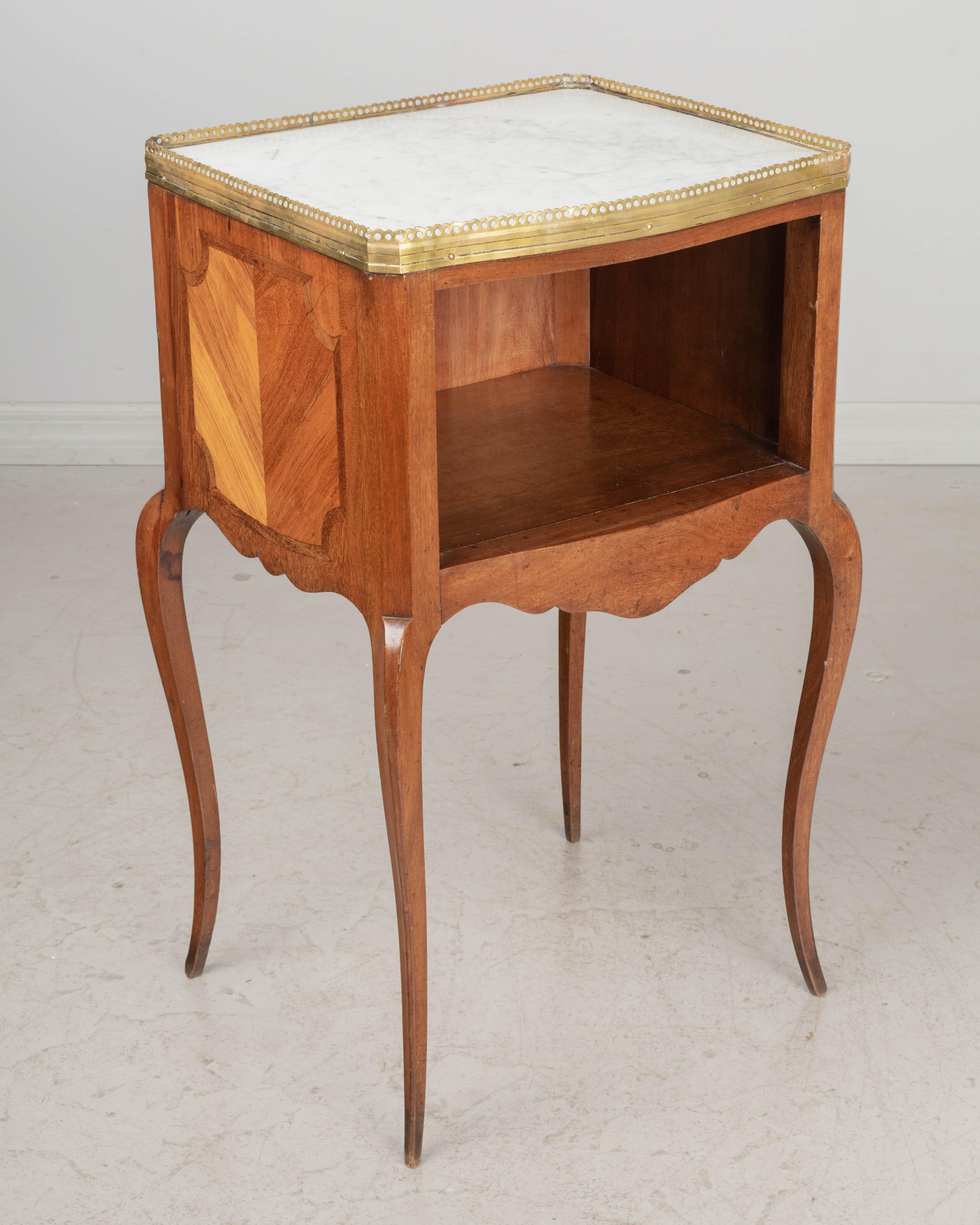 A Louis XV style French marquetry side table made of inlaid veneer of mahogany. Open niche in front and finished back. White marble top with polished bronze gallery. Elegant slender cabriole legs. Good quality and craftsmanship. circa 1920-1930.