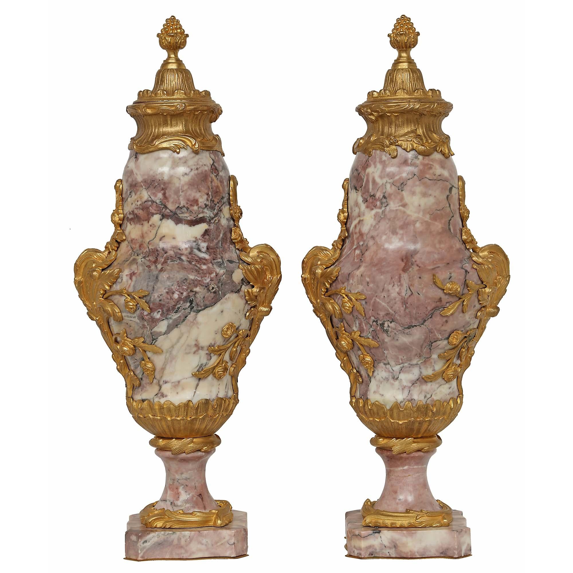 A pair of impressive French mid 19th century Louis XV st. ormolu and Bréche de Violette marble cassolettes. Each is raised on a square Bréche Violette marble base with concave corners and ormolu trim. The marble socle is adorned with an ormolu