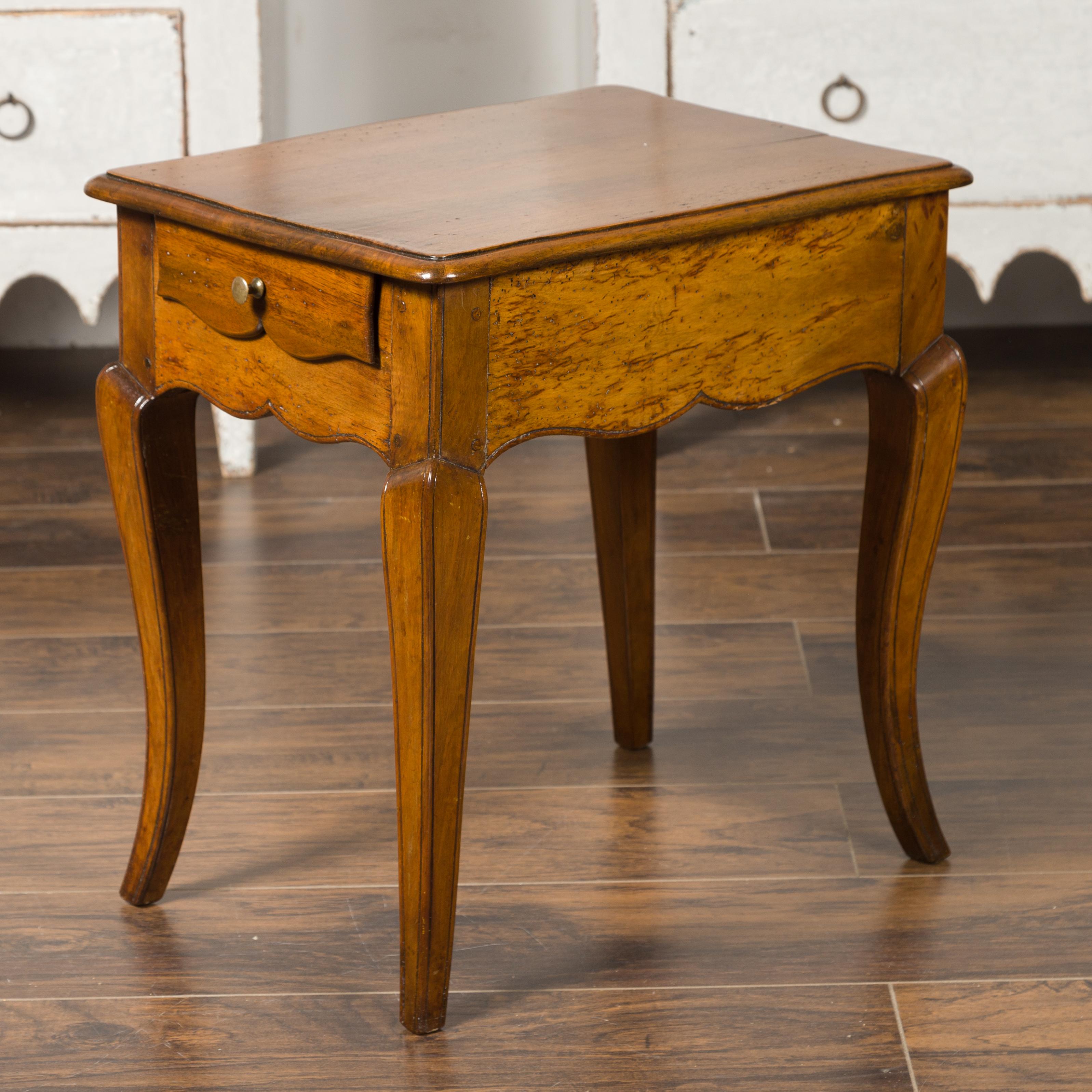 A French Louis XV style walnut side table from the mid-20th century, with long single drawer, cabriole legs and carved apron. Born in France during the midcentury period, this table features the stylistic characteristics of the Louis XV era. A
