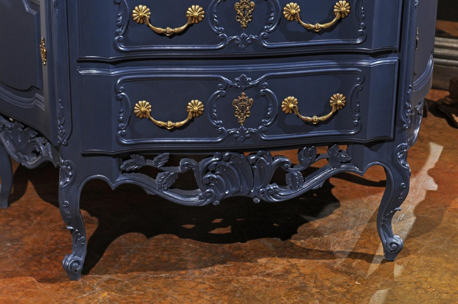 A French Louis XV style midnight blue painted two-drawer commode from the 20th century, with canted sides, carved motifs and brass hardware. Born in France during the 20th century, this exquisite commode features a sinuous top with beveled edges,