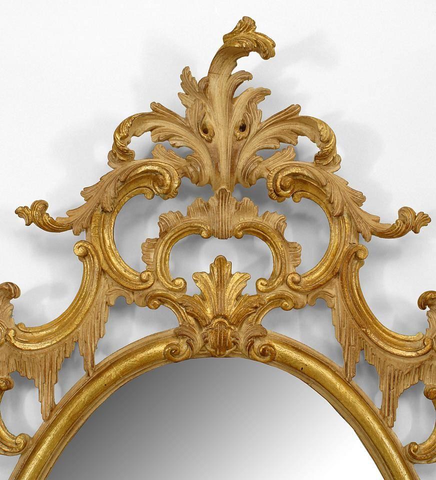 French Louis XV-style (20th Century) stripped and gilt trimmed oval wall mirror with filigree scroll design border and pediment top.
