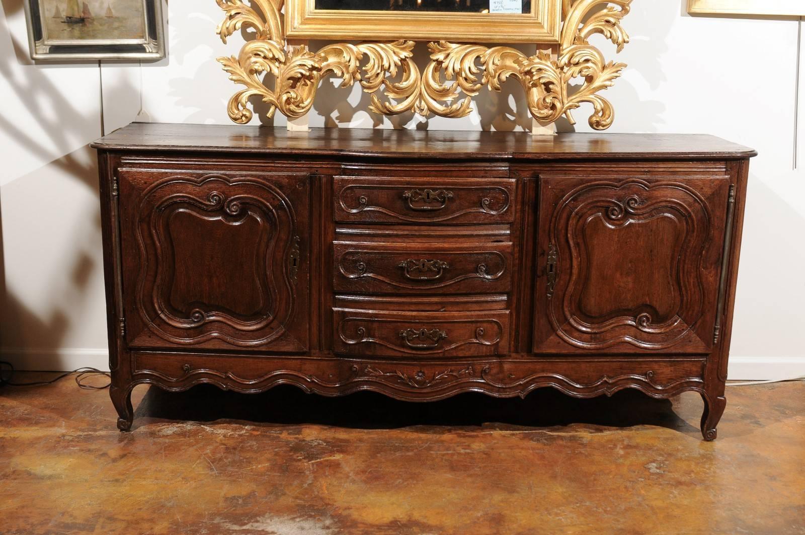 A French Louis XV style two-door and three-drawer sideboard in ¼ sawn oak from the second half of the 18th century. This exquisite French oak sideboard features a shaped top with rounded edges sitting above two doors flanking three central drawers.