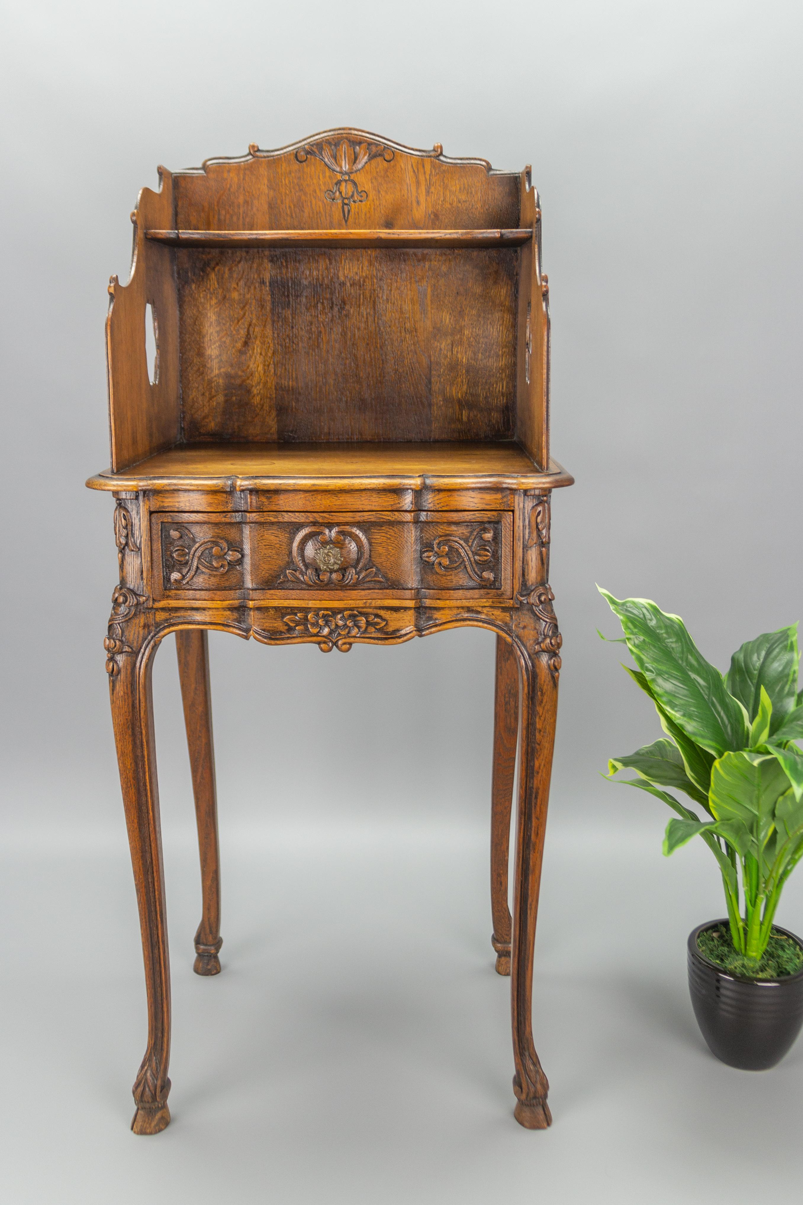 Charming French Louis XV or Rococo style nightstand or side table made of oak with beautiful carvings. The scalloped top shelf above open recess with a single drawer. Raised on graceful cabriole legs.
Dimensions: Height: 90 cm / 35.43 in; width: 40