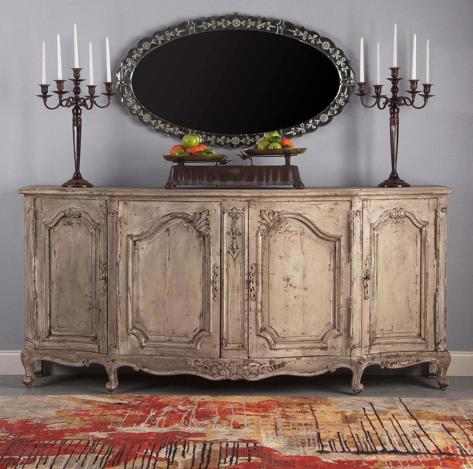 A marvelous, large antique Louis XV style painted enfilade buffet, French, circa 1900. Thick walnut construction with oak planks used at the paneled back and for shelving. Heavily distressed painting throughout in creamy gray tones. The piece is