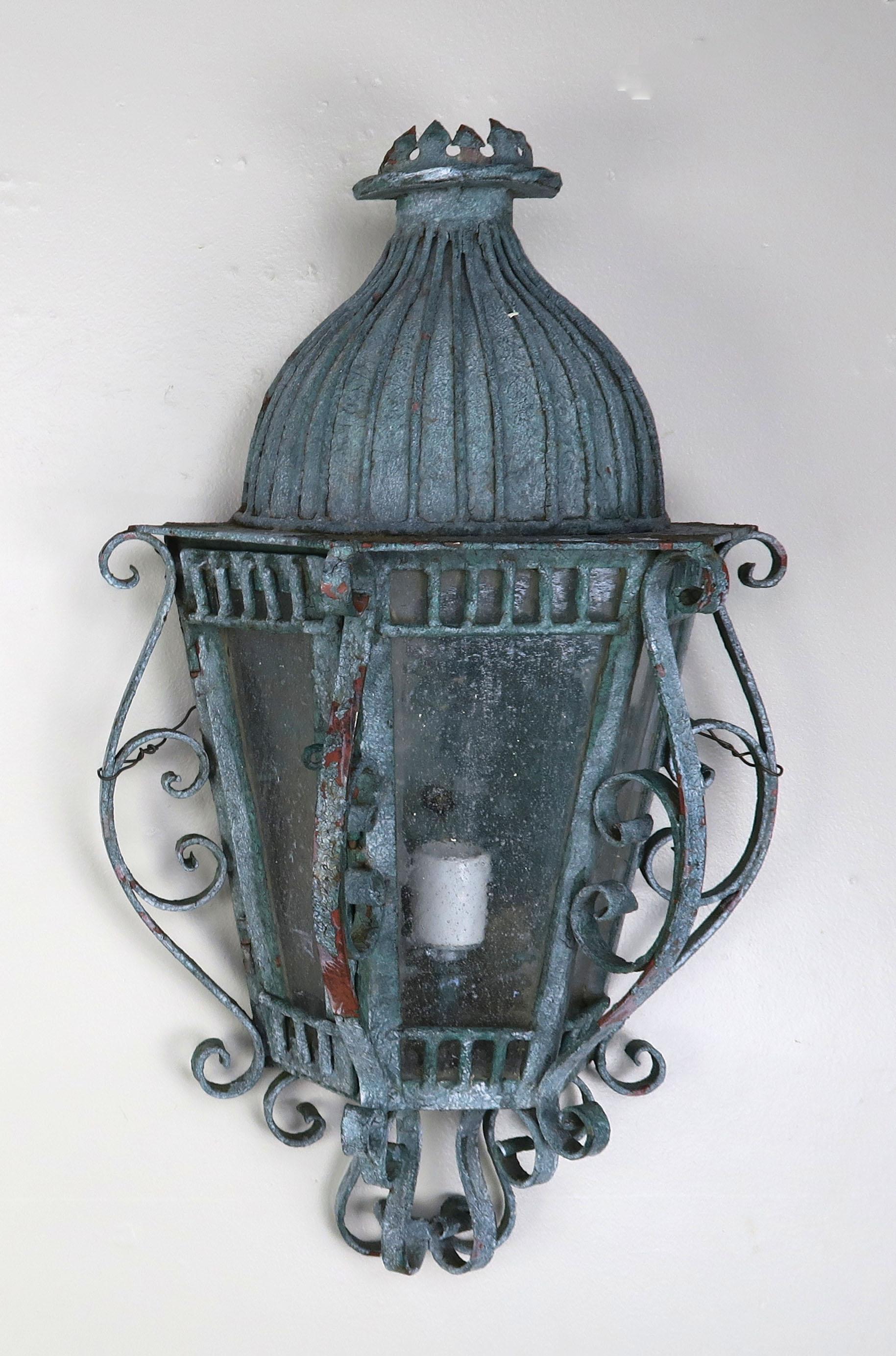 Pair of French Louis XV style painted handwrought iron sconces with original pitted glass. Beautiful scrolls adorn the fixtures and a small crown can be seen on the tops of both fixtures. The fixtures are newly rewired with new sockets and are ready