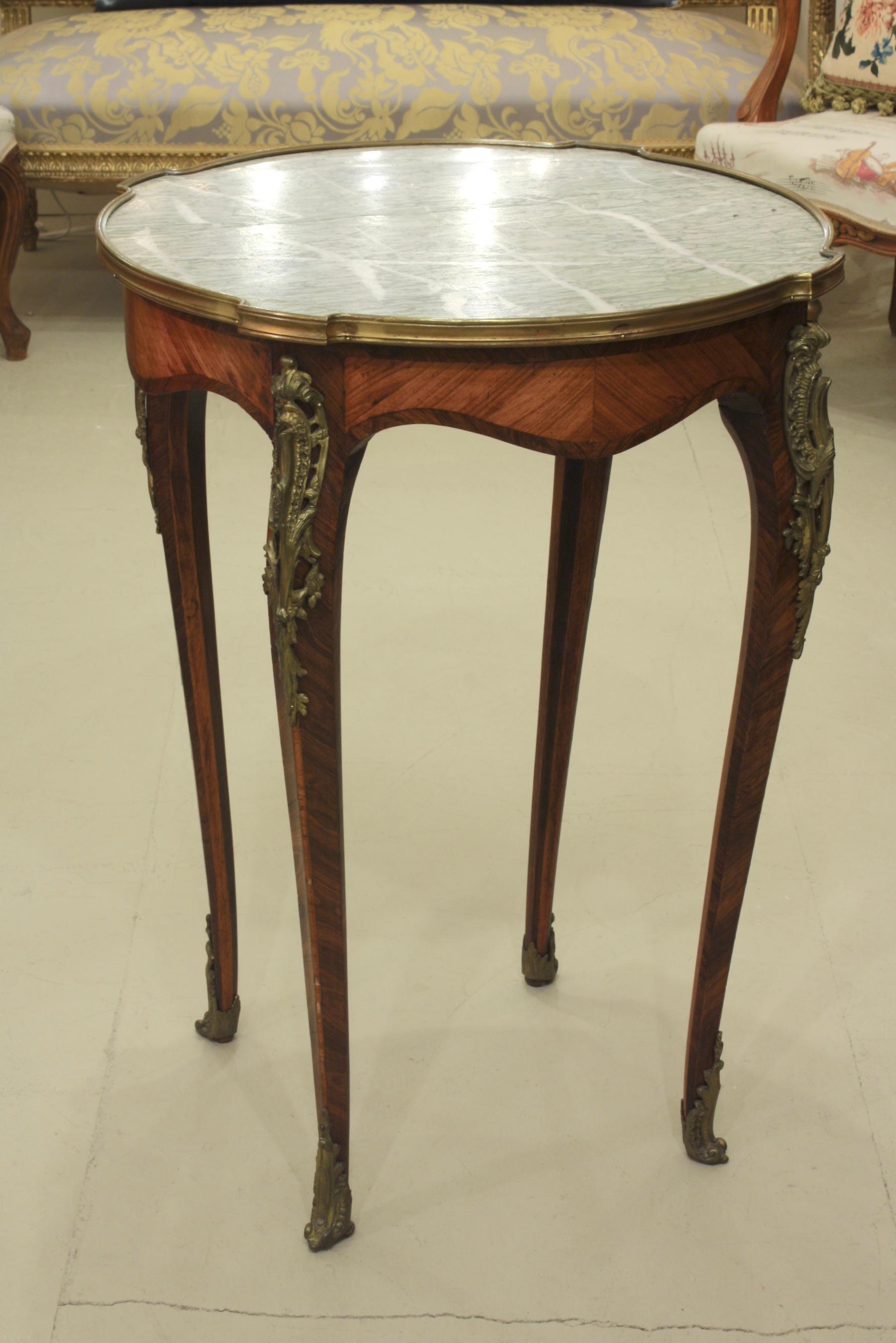 French Louis XV style gueridon or center table with nicely veined green marble top and gilt bronze mounts. The parquetry on the frieze and legs is bois de rose and bois Violette. The marble has a small crack along a vein that is not very noticeable.