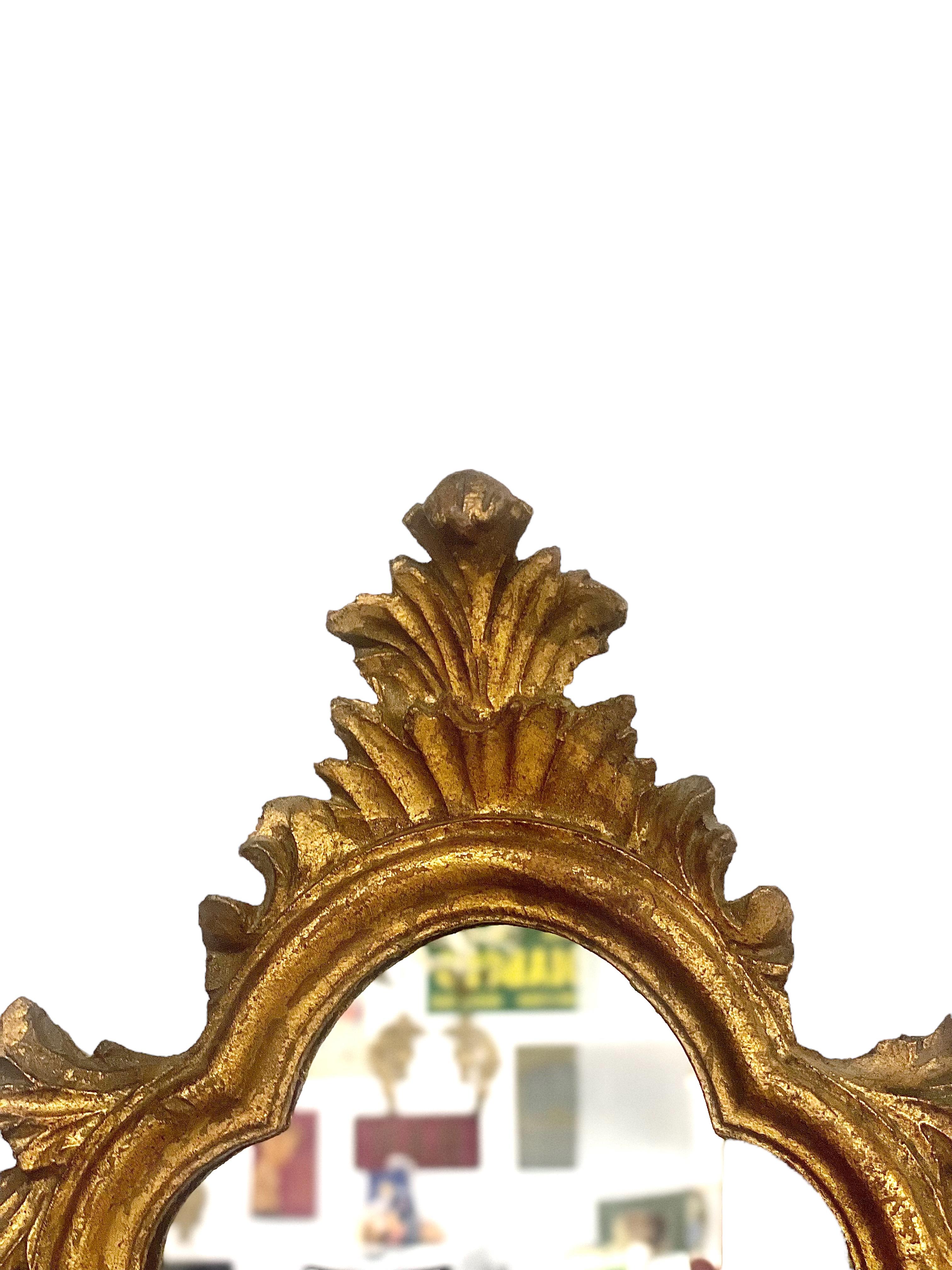 Petit miroir mural orné de style baroque Louis XV, en bois et stuc doré, au design festonné saisissant. Datant du XVIIIe siècle, ce petit miroir élégant s'inscrit magnifiquement dans un cadre orné et sculpté à la main. Il est surmonté d'une crête
