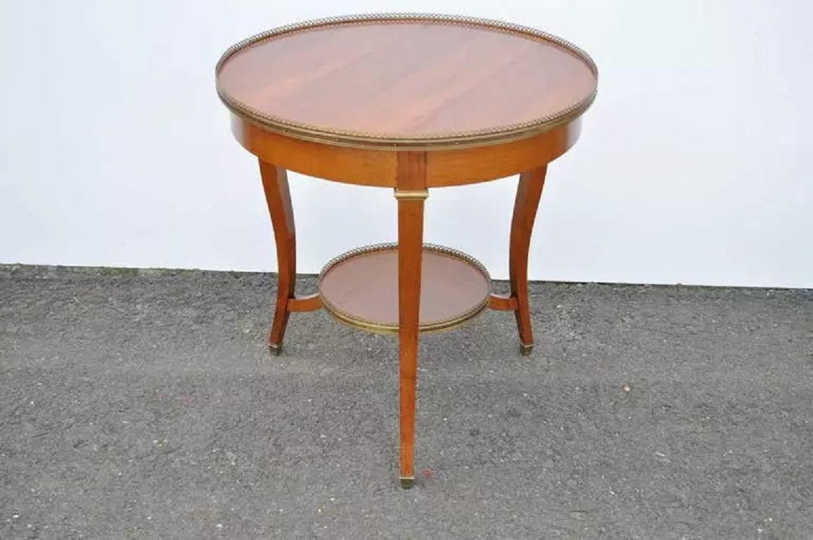 Remarquable Table Bouillotte Ronde à 2 Niveaux de Qualité avec bronze doré dans le style Louis XV / Pays Français. Cet article se caractérise par une construction en cerisier massif de qualité supérieure, une double galerie en bronze, des pieds