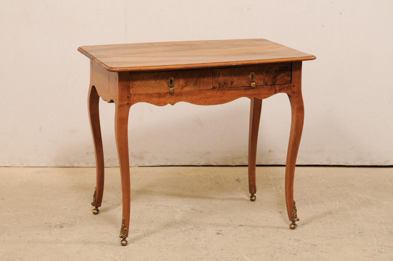 A French side table with two drawers from the turn of the 19th and 20th century. This elegant French Louis XV Style side table features a rectangular-shaped top with curved edges, atop a skirt which houses two drawers at one side, and is beautifully