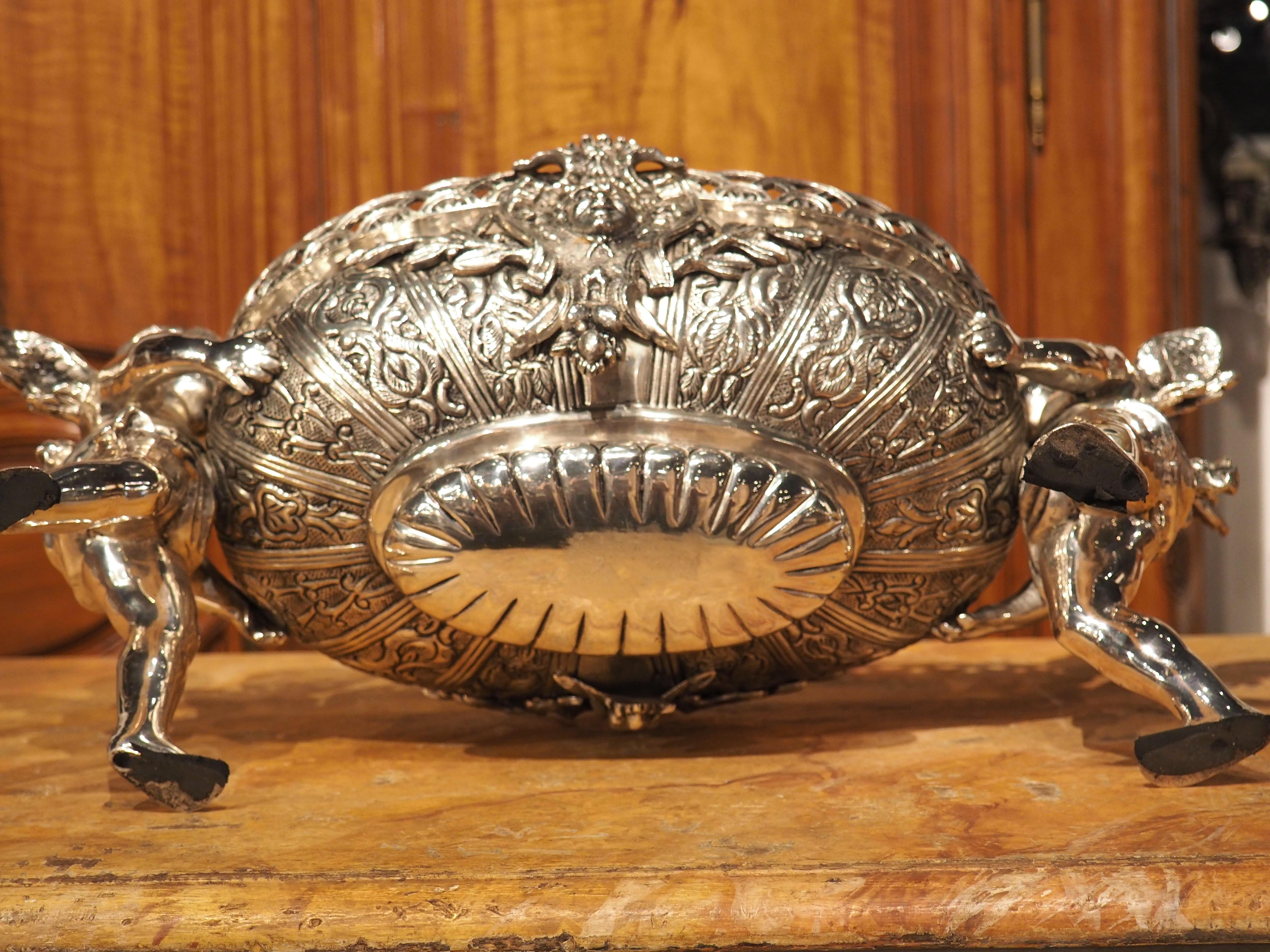 This silvered bronze French jardiniere has a lovely shimmering patina that augments the Louis XV-style motifs. Two winged putti form support legs to the ovate bowl adorned with a repeating and pierced niche that encircles the opening, interrupted