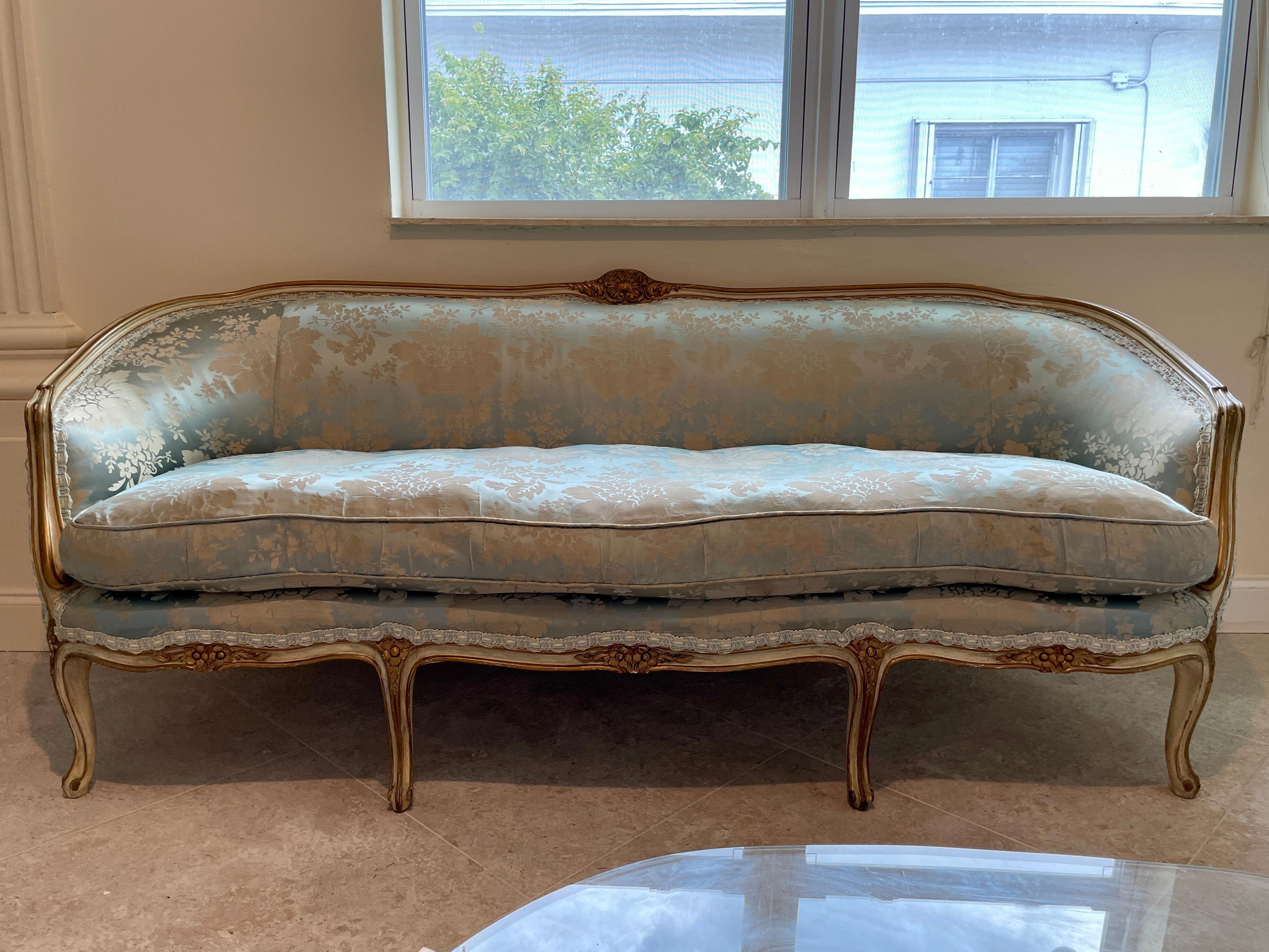 Gorgeous French Louis XV style sofa in blue silk Damask with super comfortable down cushion. Original painted finish is off white and gold details. There are some discolored fabric sections as it is the original upholstery, but could be kept as is