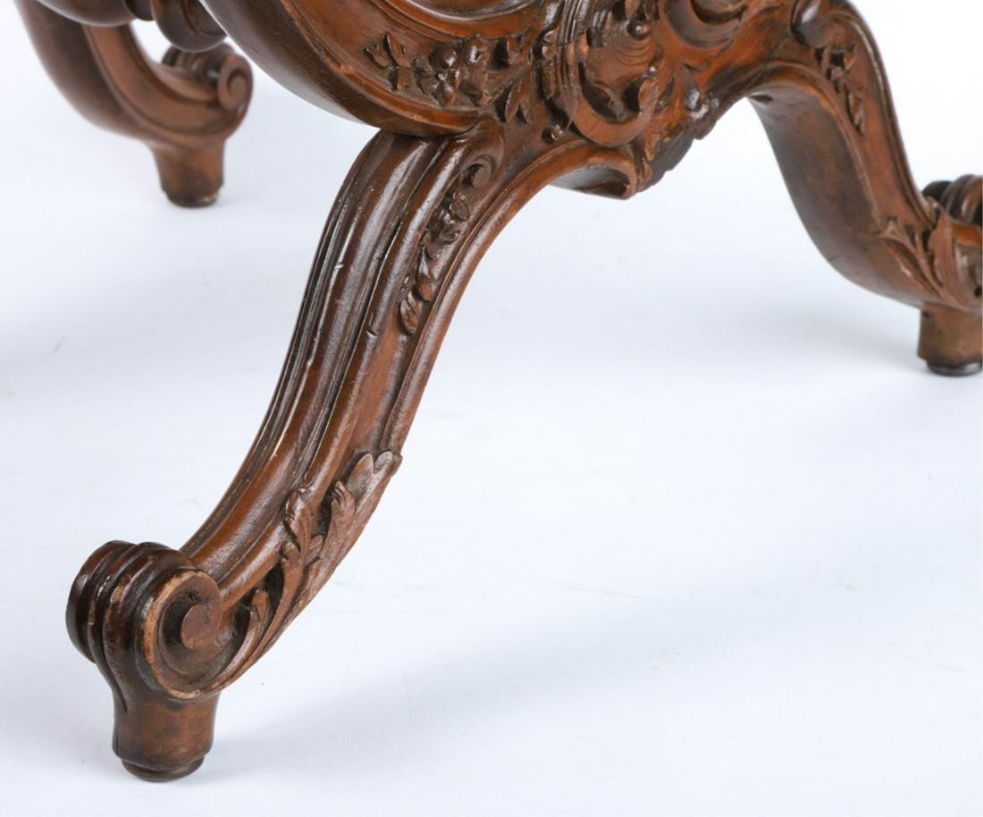 A French X-form tabouret in walnut, with upholstered seat, the base carved with rococo scrolls and volutes and supported by a turned cross stretcher, circa 1870. Napoleon III period.