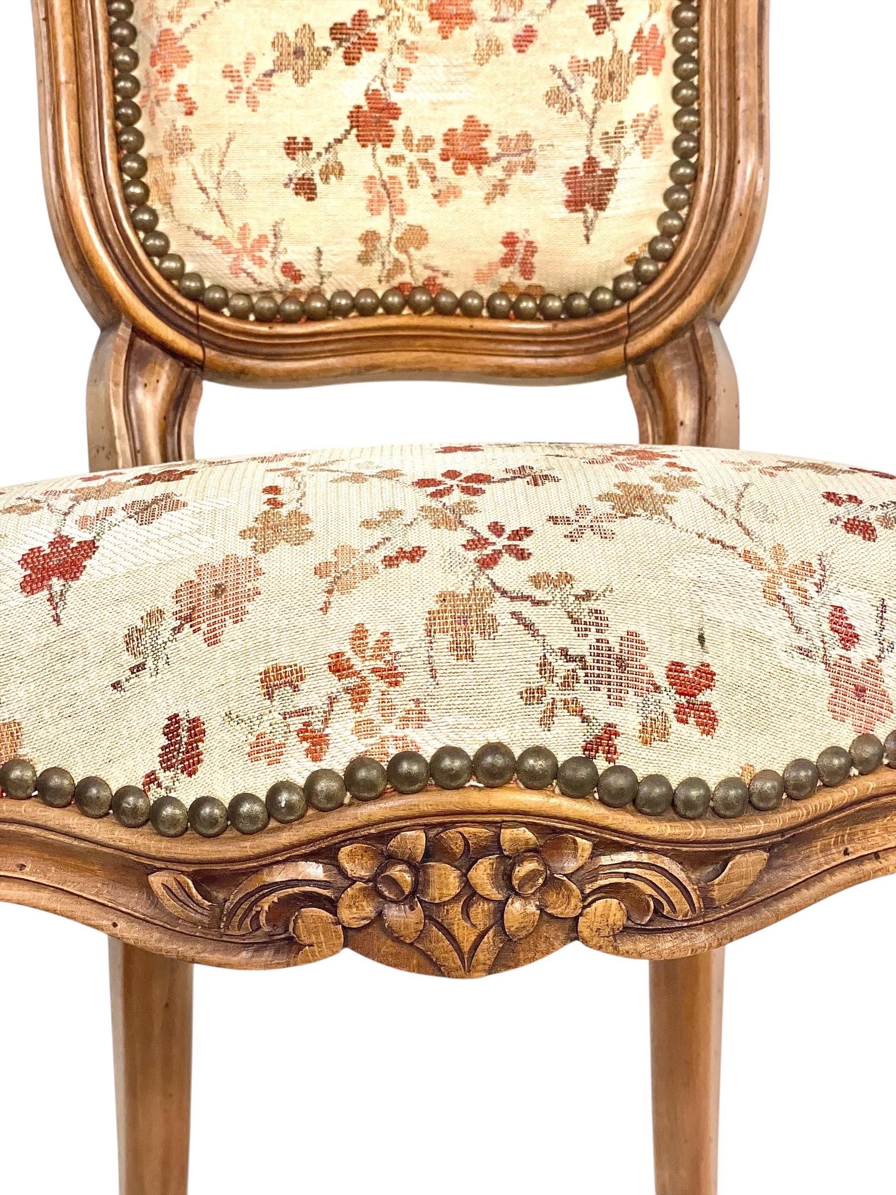 Questa affascinante sedia da bambino francese, realizzata in legno di faggio e risalente alla seconda metà del XIX secolo (circa 1870), riflette l'eleganza dello stile revival Luigi XV. La struttura è riccamente intagliata con motivi floreali sul