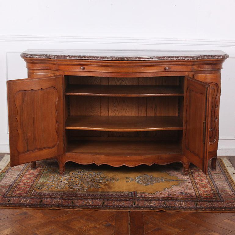 Louis XV style serpentine-profile walnut buffet with beautiful original shaped 'Rouge Royale' marble top, having four curved panelled doors opening to reveal adjustable shelves and with a single upper drawer. Shaped and carved lower apron and carved