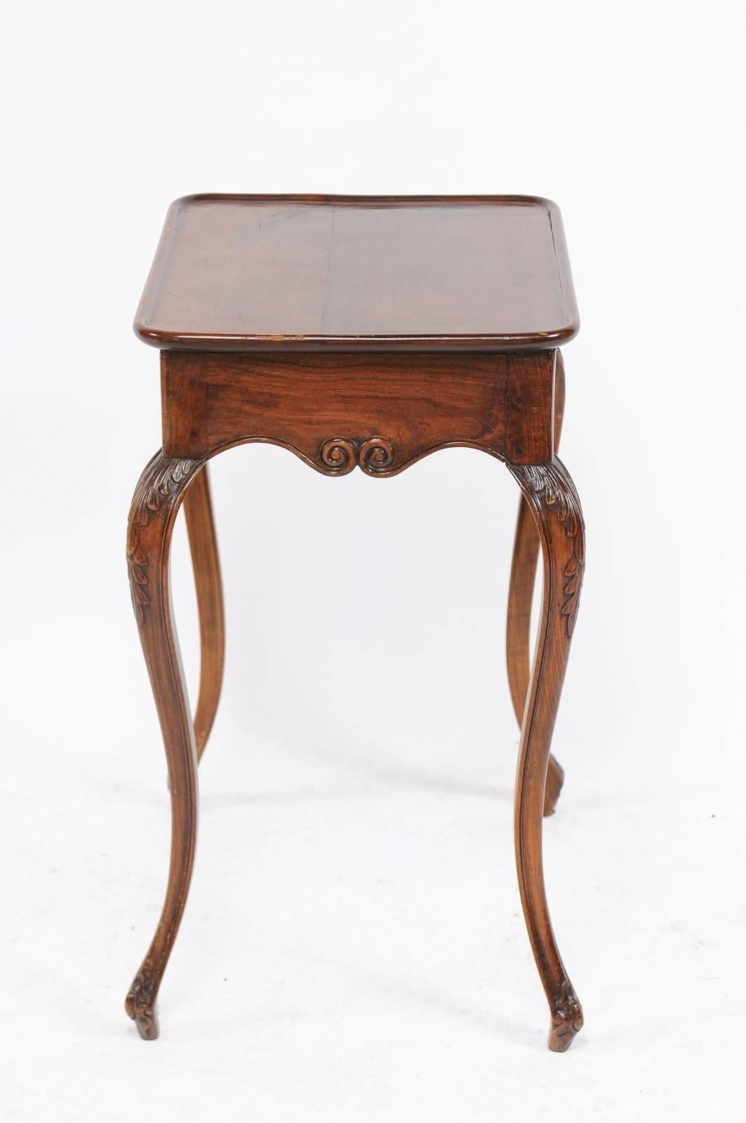 A French Louis XV style walnut side table from the 19th century with tray top, carved apron and cabriole legs carved with acanthus leaves. We’re not sure what we loved first about this 19th century Louis XV walnut table: its long, flirty legs or the