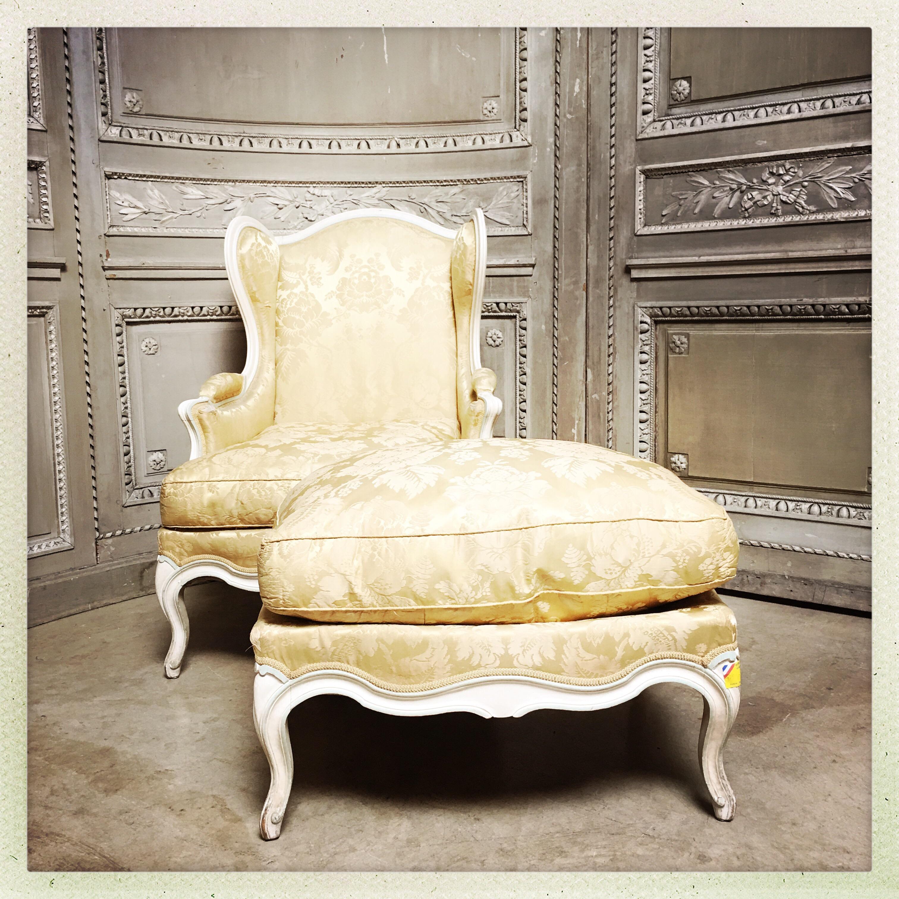 A French Louis XV style winged bergere with a matching ottoman all with a charming painted finish of cream and light blue.