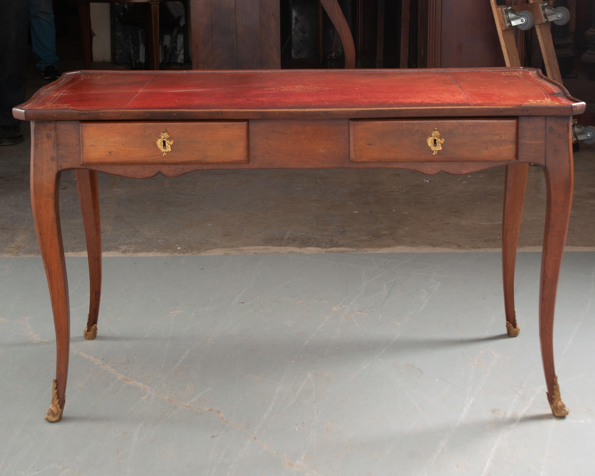 Louis XV style writing desk from France, circa 1840, will elevate any home office or library to the next level of sophistication. Gorgeous red leather writing surface with gold tooling and a breakfront lip provides an inviting space to work at. The
