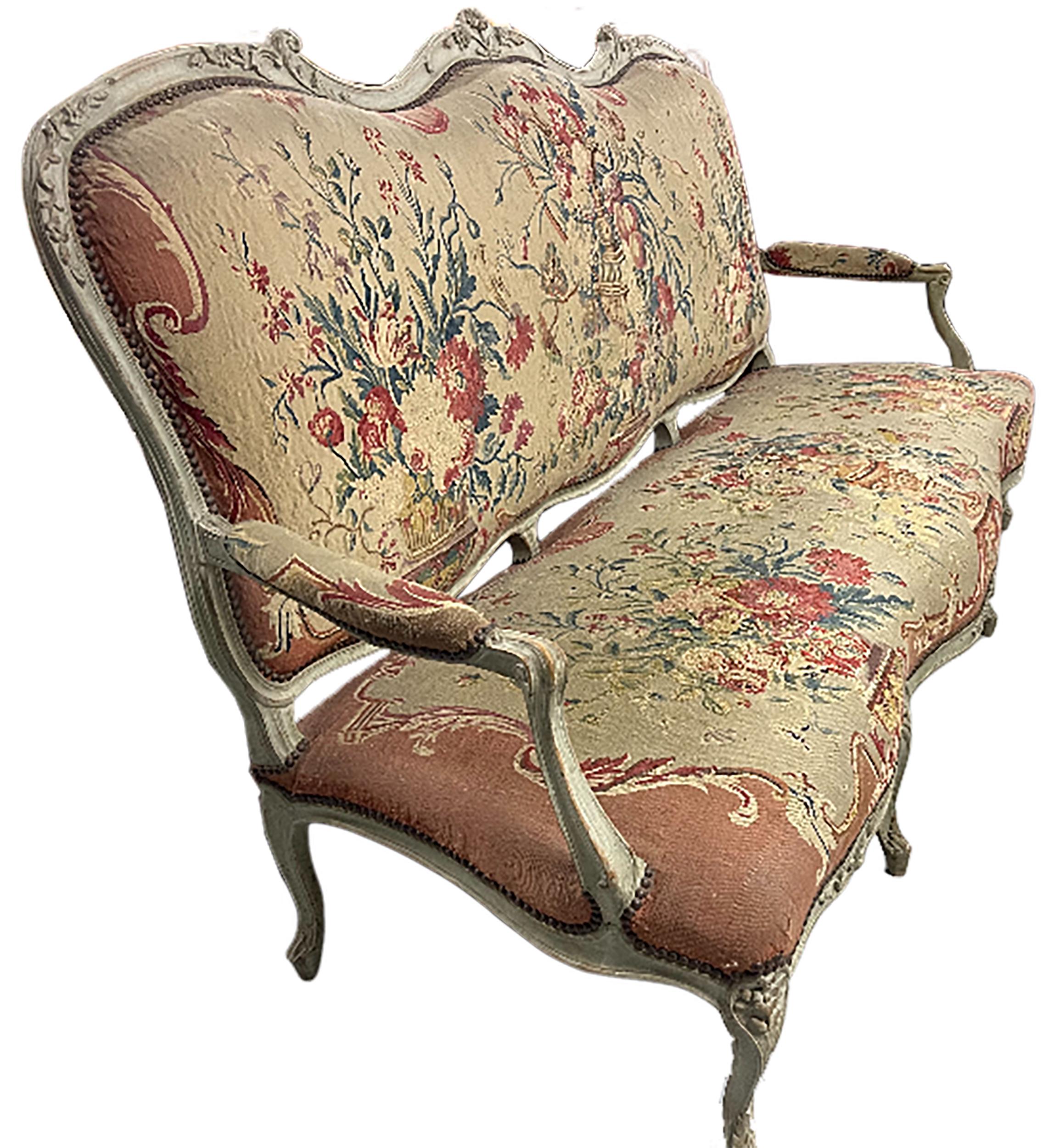 An elegant French Louis XV Style tapestry/canape settee. Amber aubusson tapestry upholstery with floral patterns. Accents of red clay colors on the edges of the upholstery. Elegantly carved and painted armrests and cabriole legs. Plaid pattern