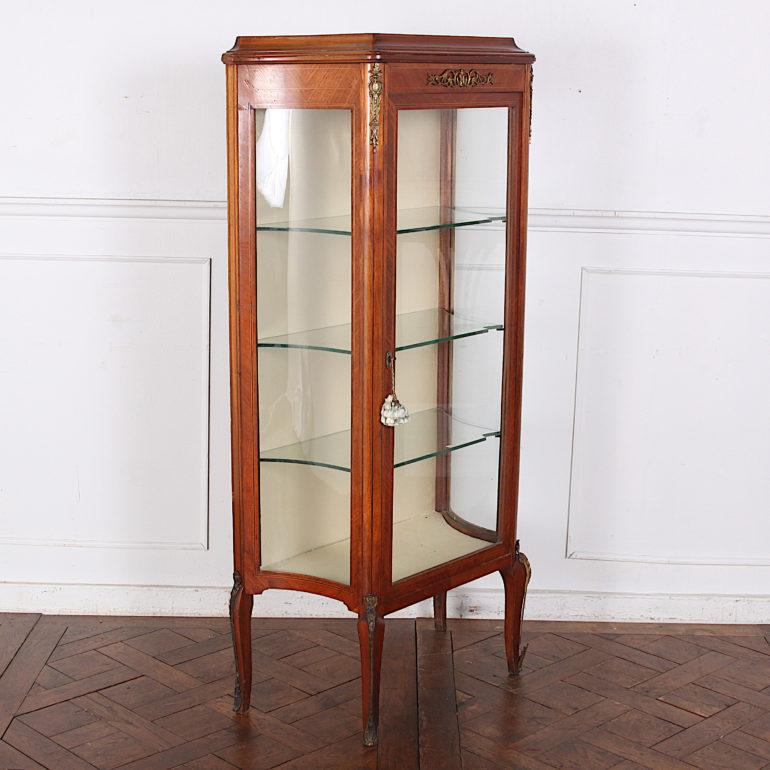 A Louis XV style vitrine with book-matched kingwood veneered panels and inlaid ebony and boxwood stringing. The concave sides have conforming curved glass and the piece is accented with gilt bronze mounts to the legs and case. Three glass shelves.