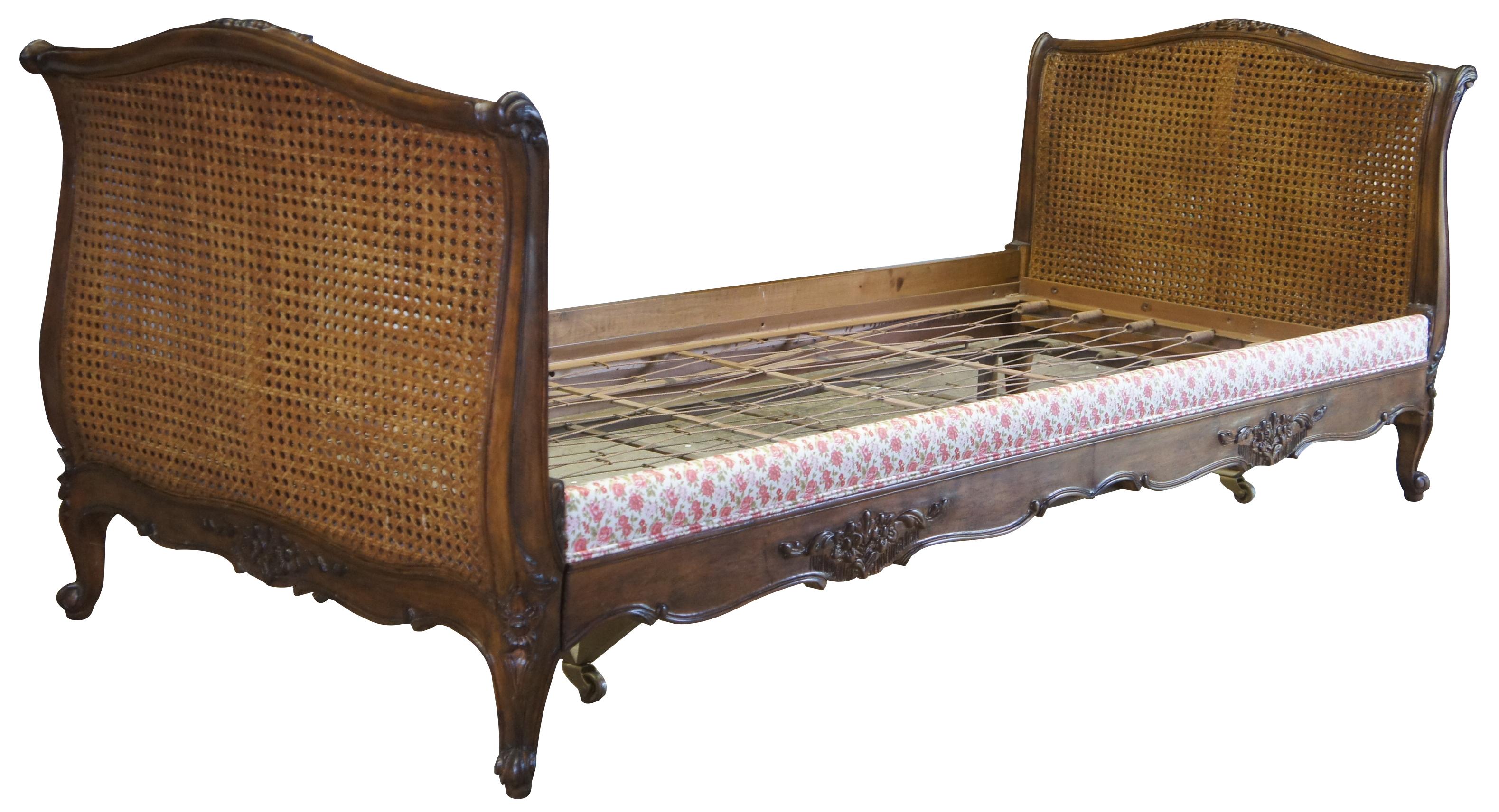 Mid-20th century French trundle bed. Made from walnut with a flared frame featuring floral carvings, a rose upholstered front and caning alone each side.
     