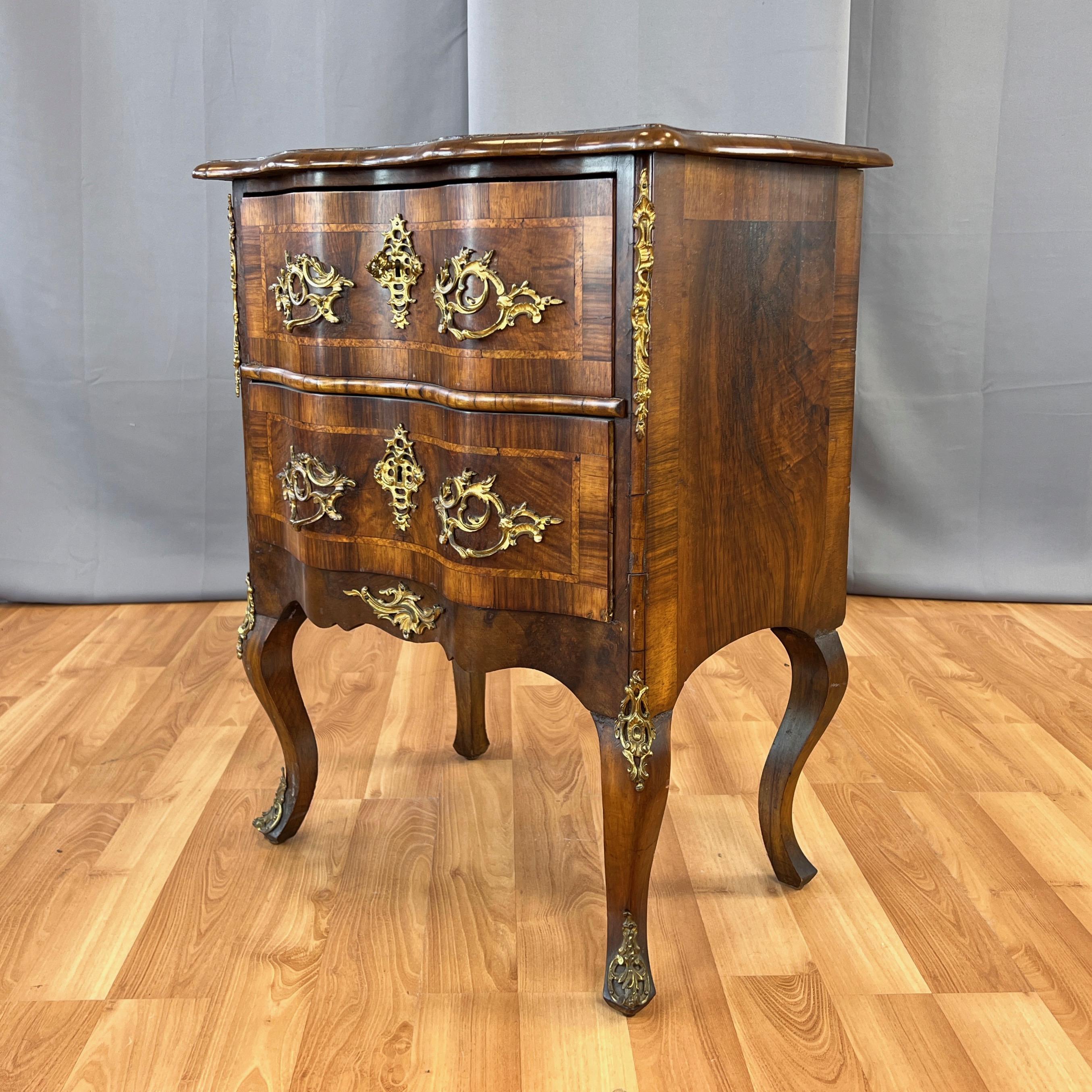 An exceptionally handsome early 19th century French Louis XV walnut, burlwood, satinwood, and fruitwood marquetry lockable two-drawer commode or petite chest with ormolu mounts and embellishments.

Dynamically figured and beautifully contrasting