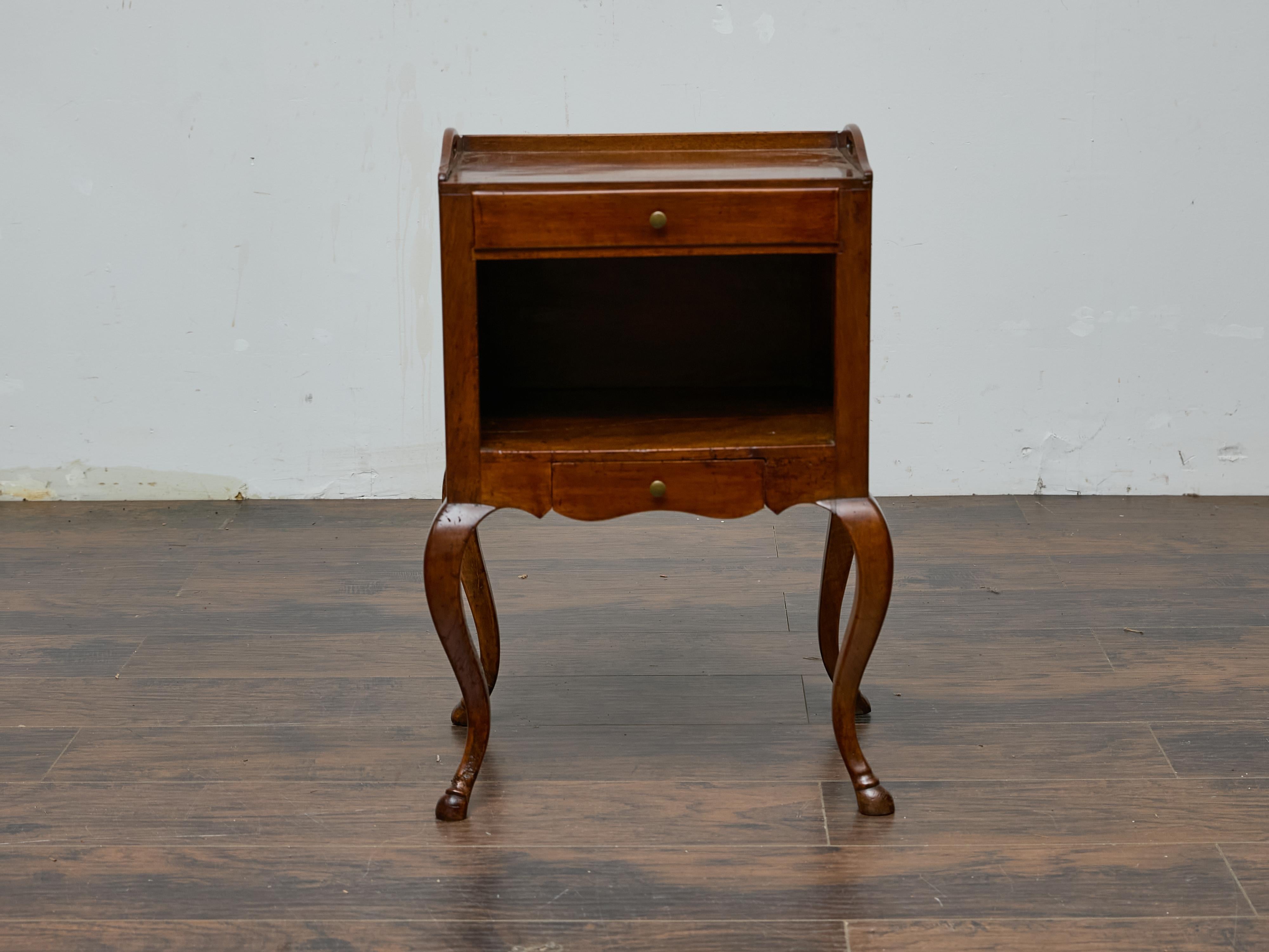 A French 19th-century Louis XV-style walnut bedside table with all the charm of its era. The delicate tray top, complete with raised edges and cutout handles, speaks to both form and function—offering an elegant yet practical surface for a bedside