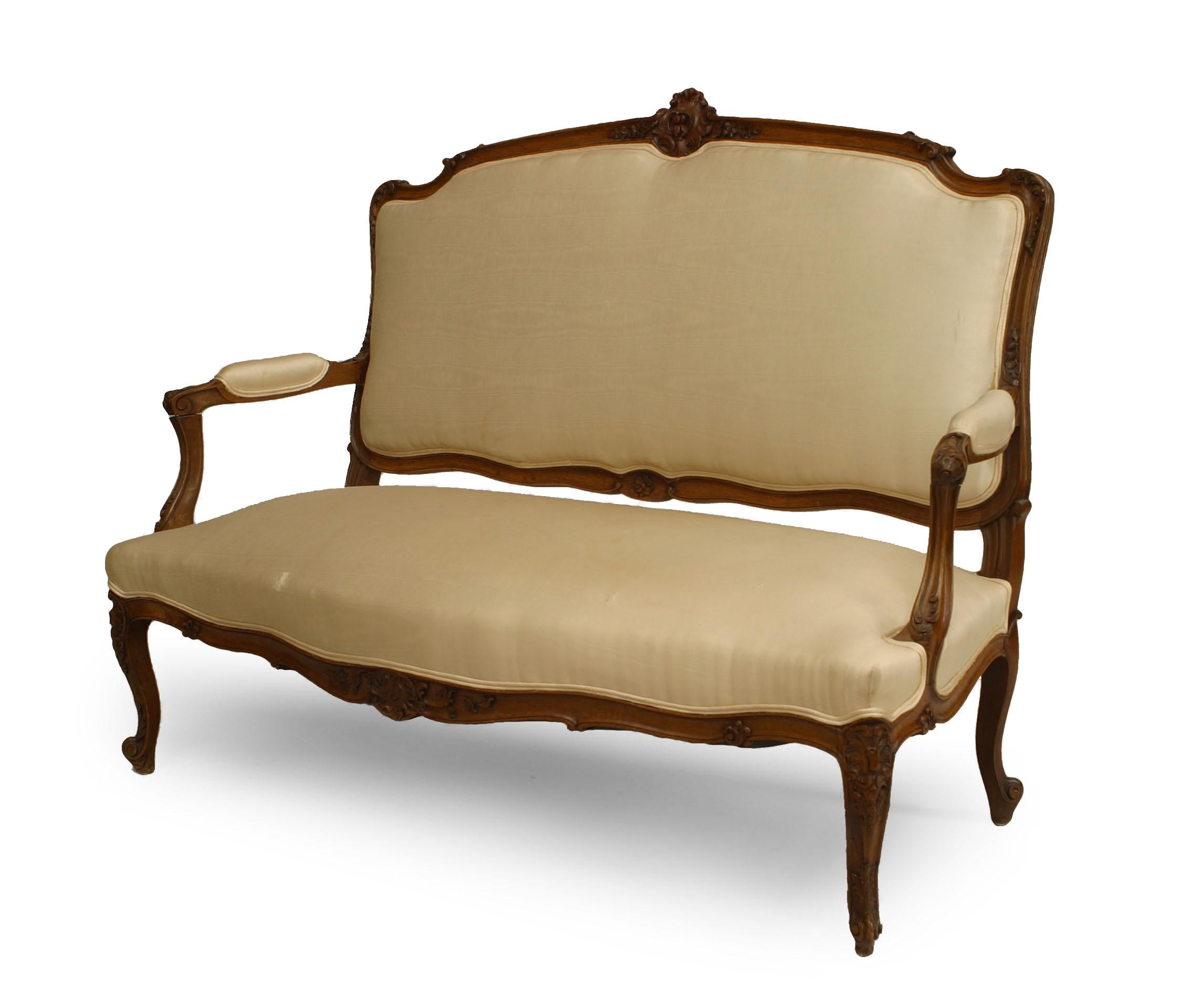 French Louis XV style (19th-20th century) walnut settee with white upholstery and carved back crest.