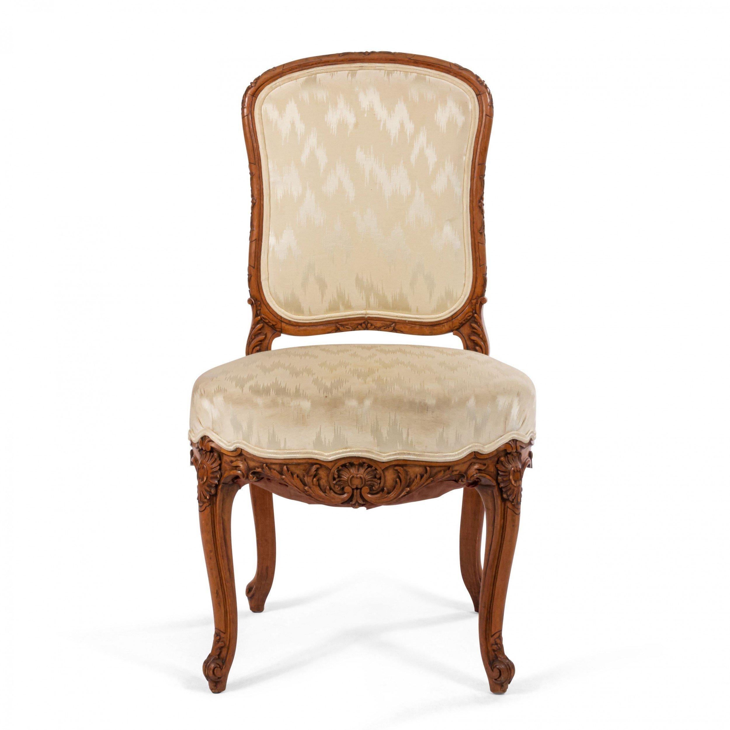 Pair of 19th century French Louis XV style walnut side chairs with a floral carved frame and upholstered seat and back.