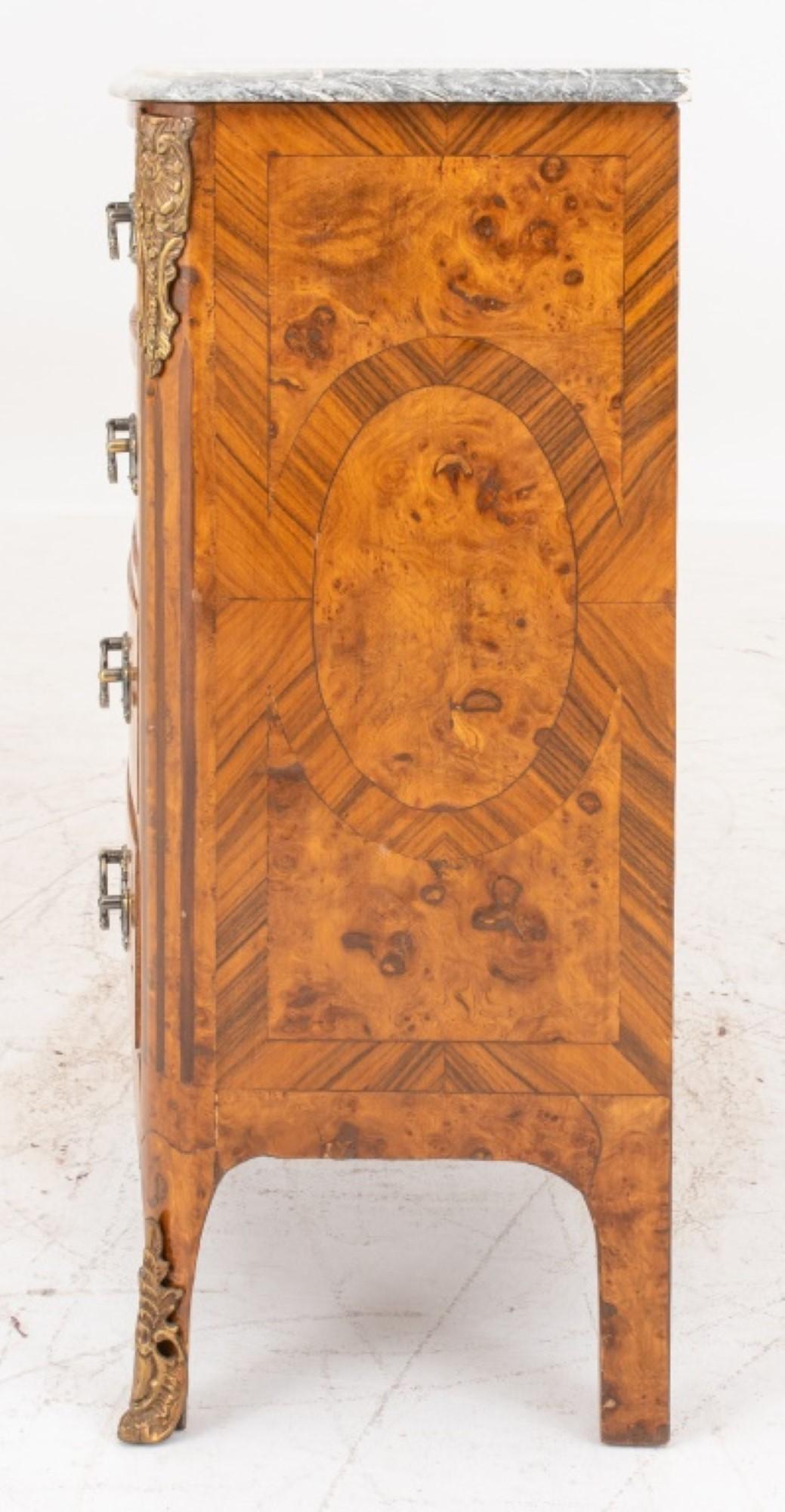 Commode de style transitionnel Louis XV / XVI à quatre tiroirs en placage de marqueterie avec chutes, tirettes et sabots en laiton doré.

Concessionnaire : S138XX