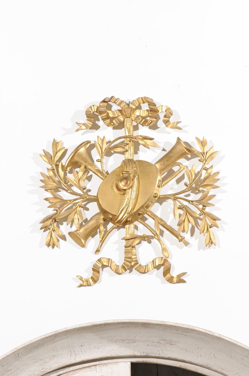 A French Louis XVI hand carved giltwood wall decoration from the second half of the 18th century, with musical trophy, ribbon and foliage. Born in France in the early years of the reign of King Louis XVI, this exquisite wall decoration features a