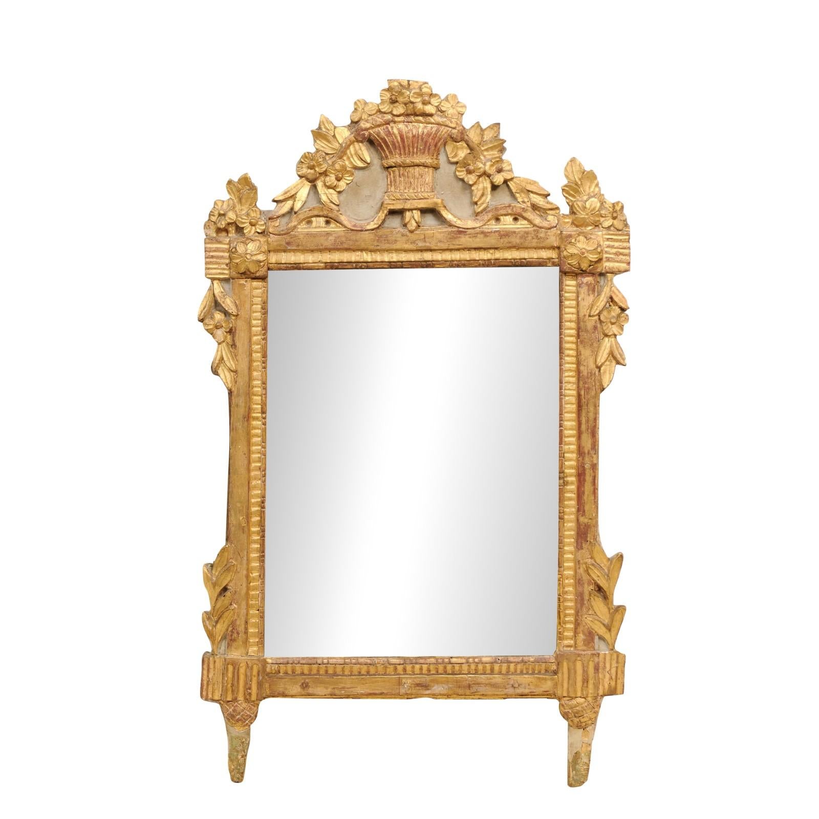 A French Louis XVI period giltwood mirror from the 18th century with carved crest depicting a bouquet of flowers falling from a wicker basket, carved foliage and old mirror plate. This stunning French Louis XVI period giltwood mirror from the 18th