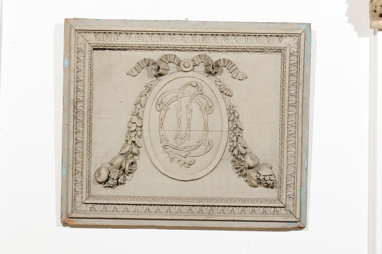 Panneau de boiseries en bois peint et sculpté à la main d'époque Louis XVI, datant de la fin du XVIIIe siècle, avec des motifs de monogrammes, de guirlandes et de fruits. Née en France au cours de la seconde moitié du XVIIIe siècle, cette exquise