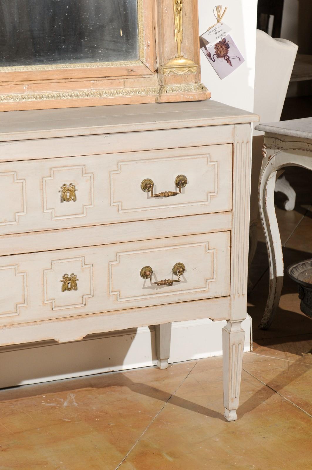 A French Louis XVI period painted two-drawer commode from the late 18th century, with fluted accents and bronze hardware. Born in France at the end of King Louis XVI's reign, this painted commode features a rectangular top sitting above two hand-cut