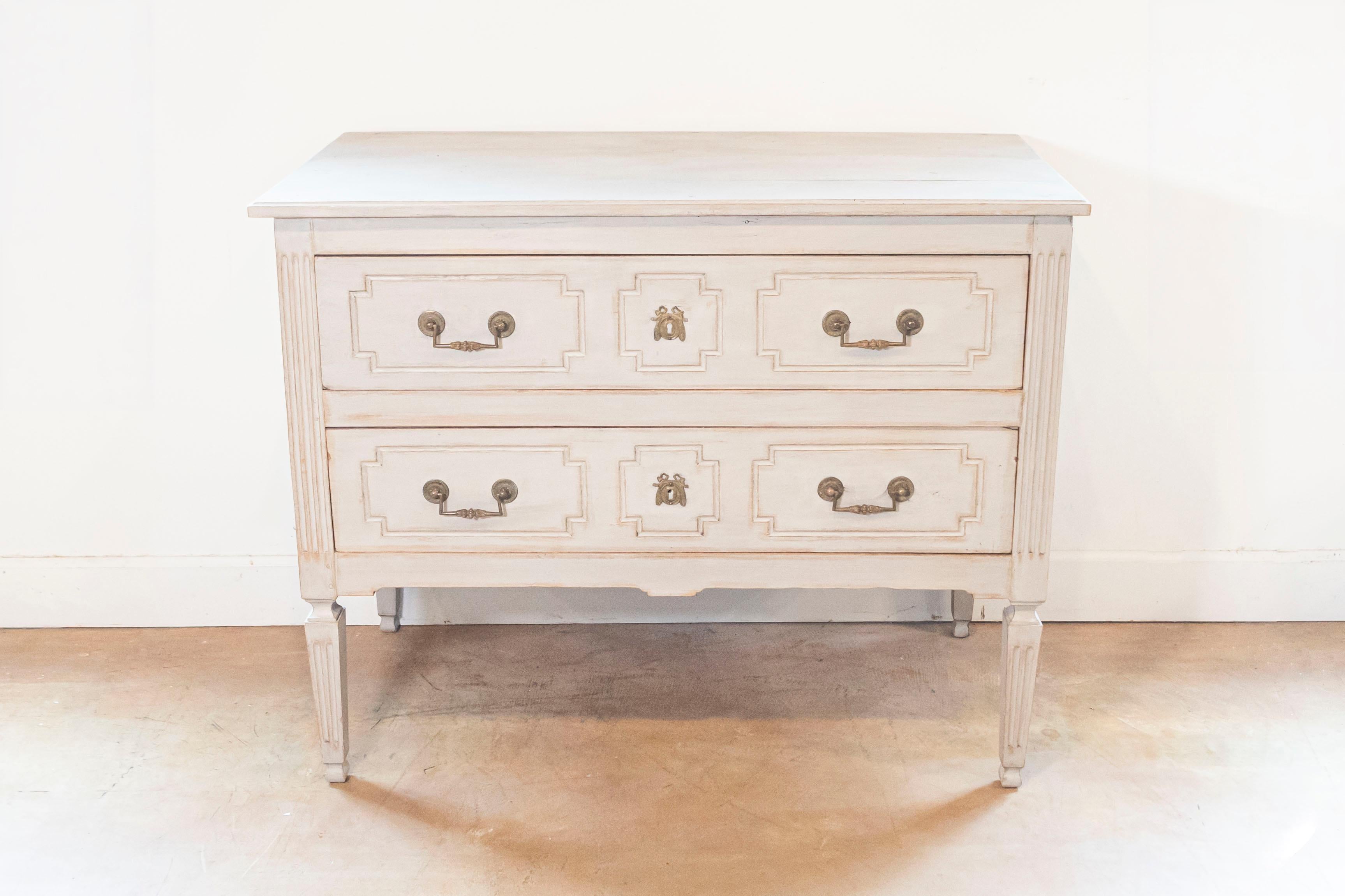 A French Louis XVI period painted two-drawer commode from the late 18th century, with fluted accents and bronze hardware. Born in France at the end of King Louis XVI's reign, this painted commode features a rectangular top sitting above two hand-cut