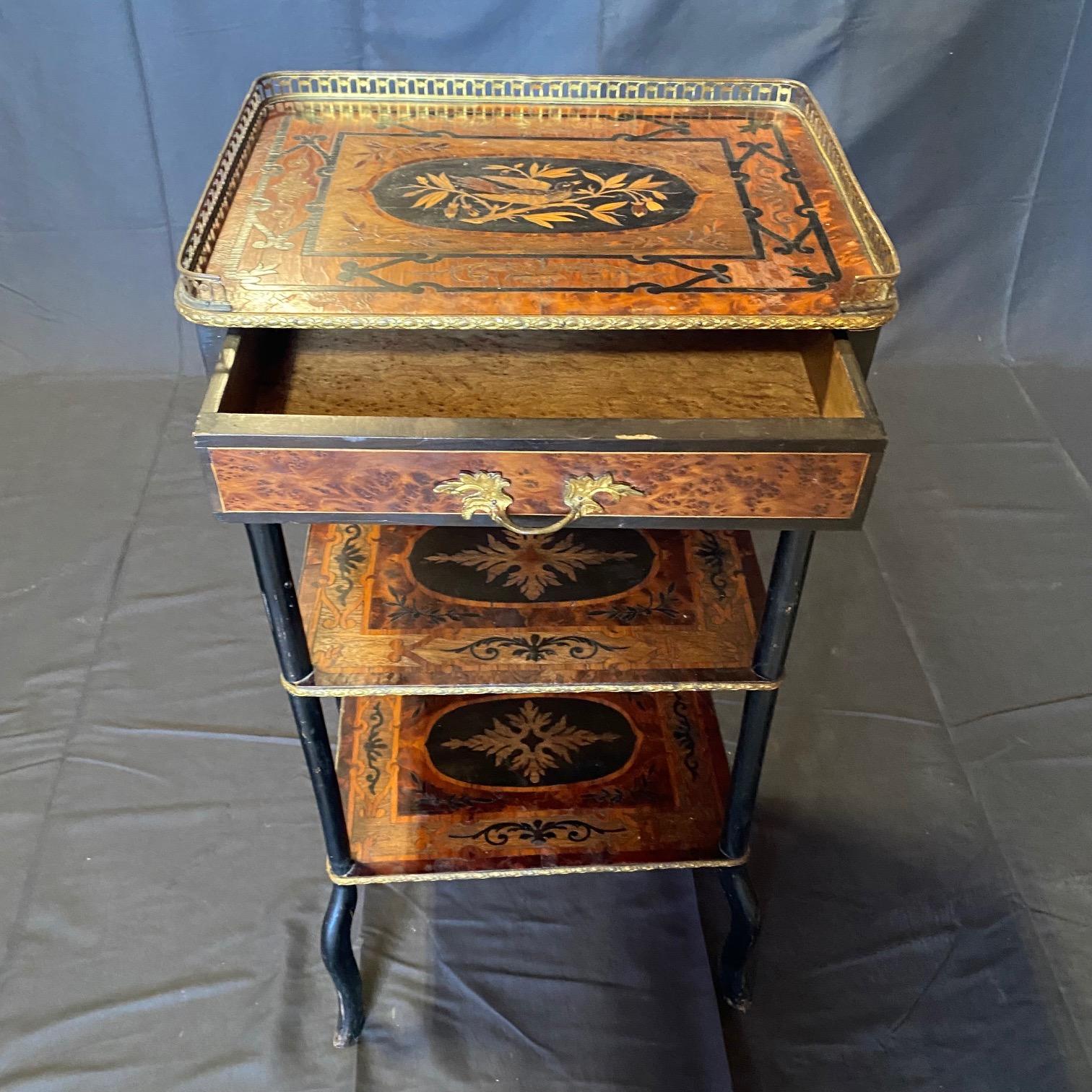 French three-tiered marquetry inlaid etagere table with brass gallery and one drawer. The top shelf depicts a beautifully inlaid bird on a branch with twigs and acorns, and the one dovetailed drawer is directly below with burlwood face and lovely
