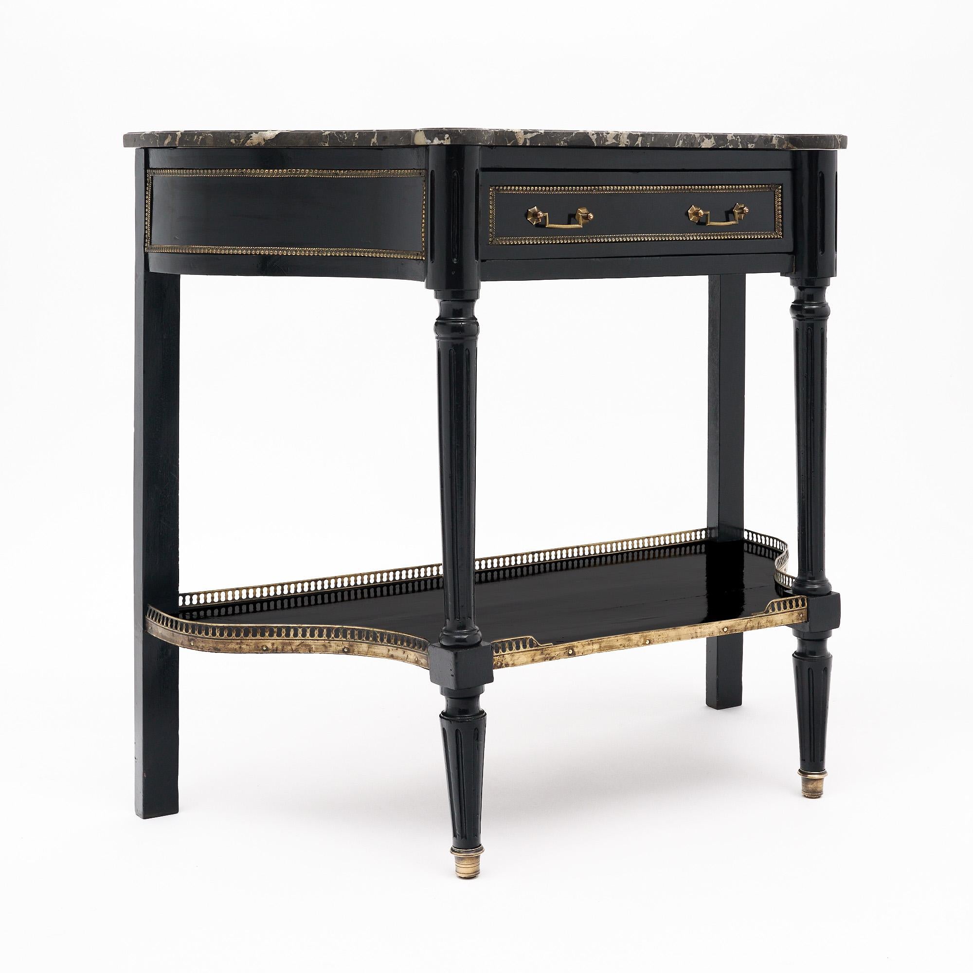 Table console de France de style Louis XVI. Cette pièce est fabriquée en bois massif, principalement en acajou. Elle a été ébonisée et finie avec un vernis français lustré de qualité muséale. Cette pièce présente des côtés concaves et un tiroir à