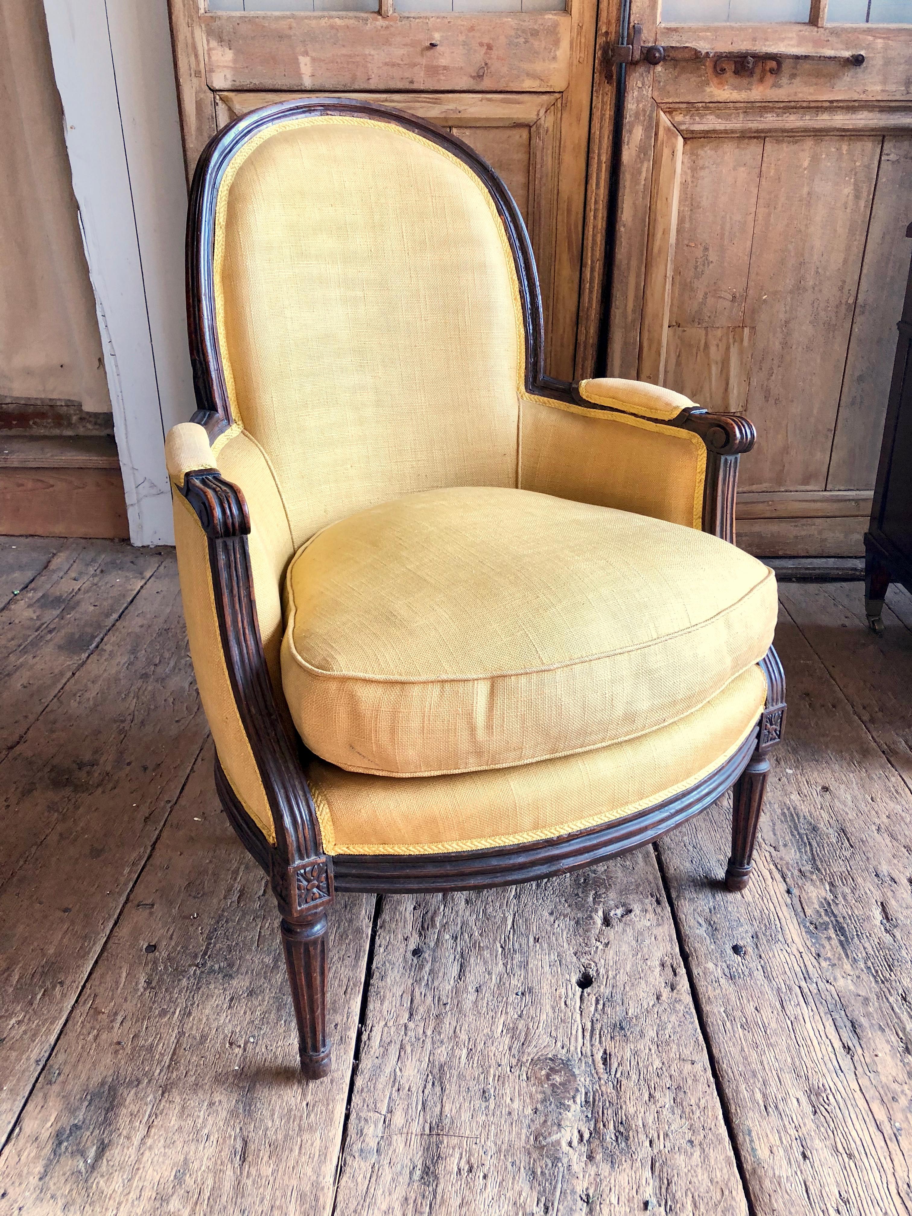 A late 18th century French Louis XVI Period bergère “gondole” in beech with old walnut finish and a great patina, upholstered in a yellow linen fabric with feather-stuffed seat cushion. Nice proportions and very comfortable.