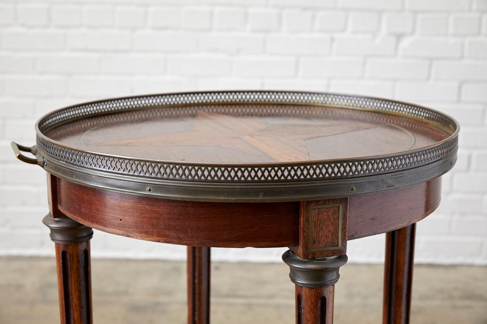 Exceptional French Louis XVI inlaid Bouillotte table or drink table. Features a bronzed galleried tray style top with handles on each side and a decorative pierced edge. The tabletop showcases the radiant mahogany grain with an inlay star motif