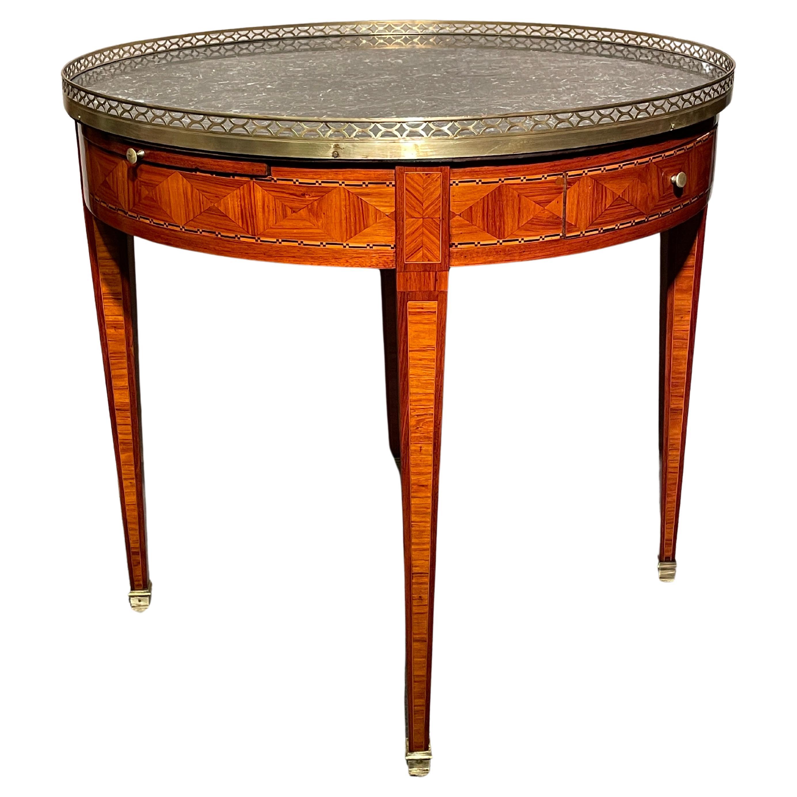 This exquisite Louis XVI Bouillotte Table, dating back to 1800, showcases the artistry of wood marquetry with inlaid bands. Adorned with a sophisticated dark grey marble top, elegantly framed by a delicate pierced brass gallery, this table is a true
