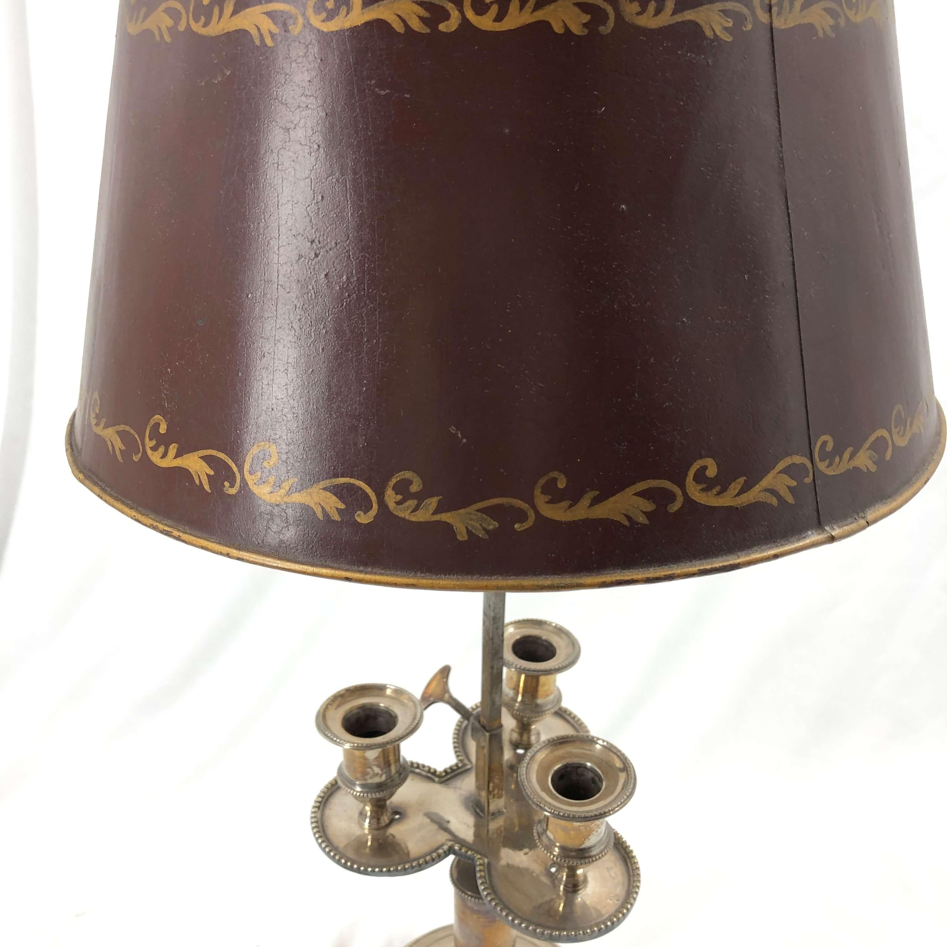 An unusual French Louis XVI silvered bronze three light Boulliotte lamp with a hand painted red and gold stenciled adjustable shade, an adjustable light height on a round plinth beaded base.