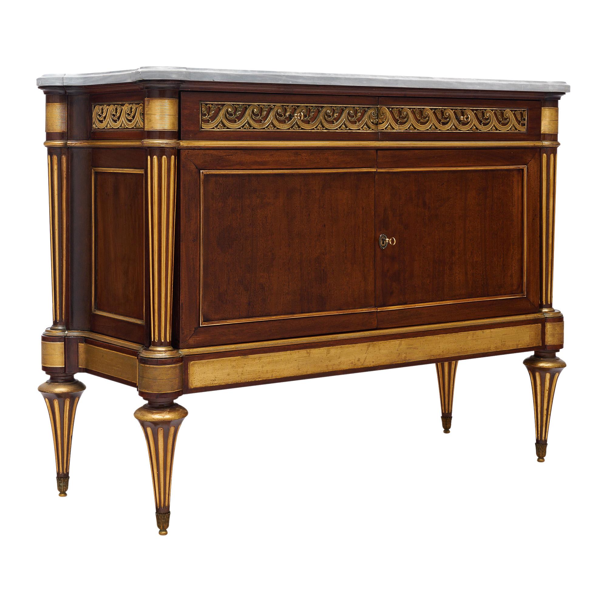 Buffet francese in stile Luigi XVI. Questo pezzo è realizzato in mogano a righe con dettagli artigianali di grande effetto. Ci sono due porte che si aprono su scaffali interni. Nella traversa i due cassetti a coda di rondine sono ornati da un