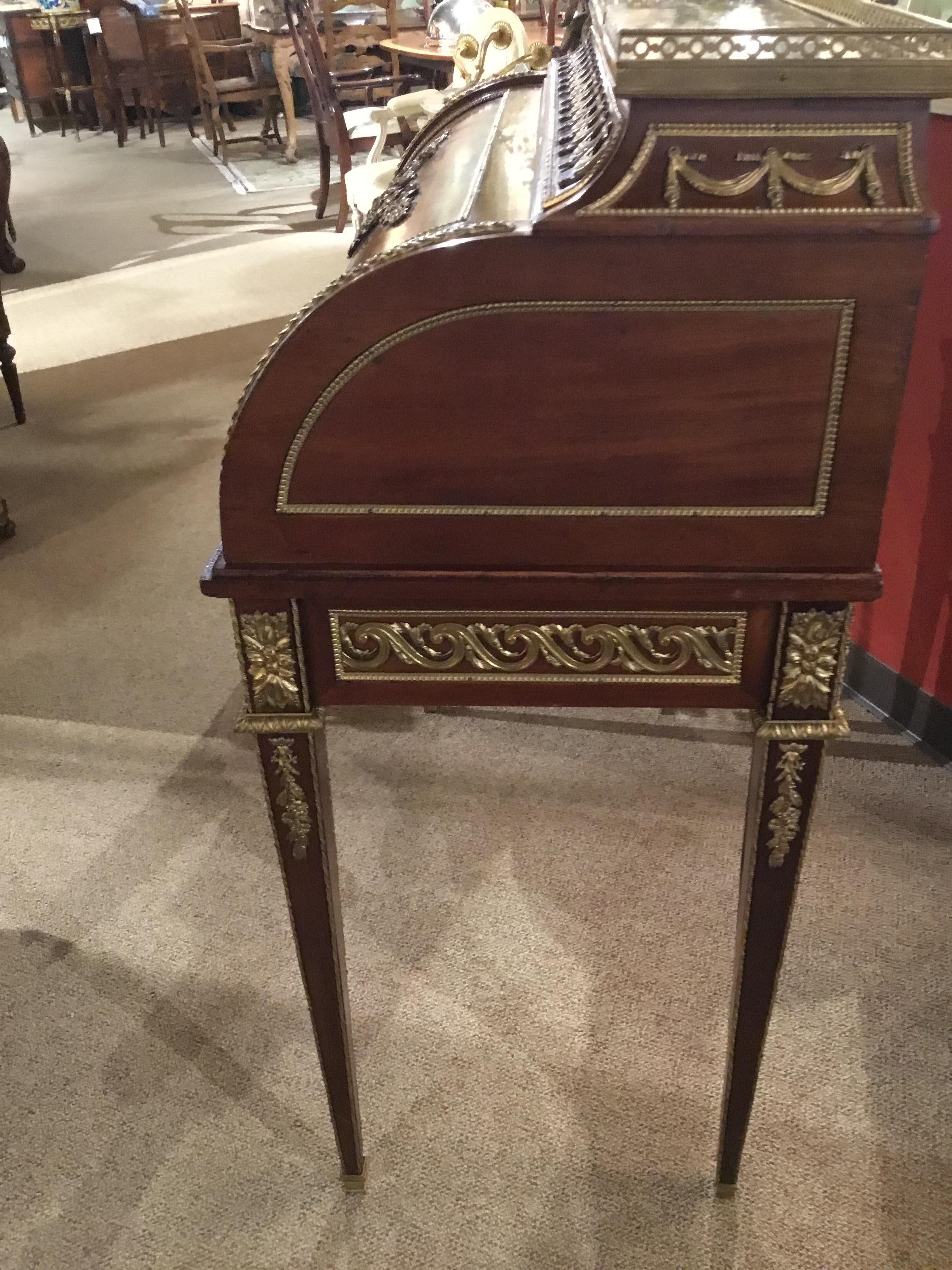 19th century desk with a Cylindre roll top opening to a leather top that pulls out for ease
In use. Gilt bronze mounts with floral gilt center decoration with wreath. Square tapered
Legs with gilt beading and bronze sabots.