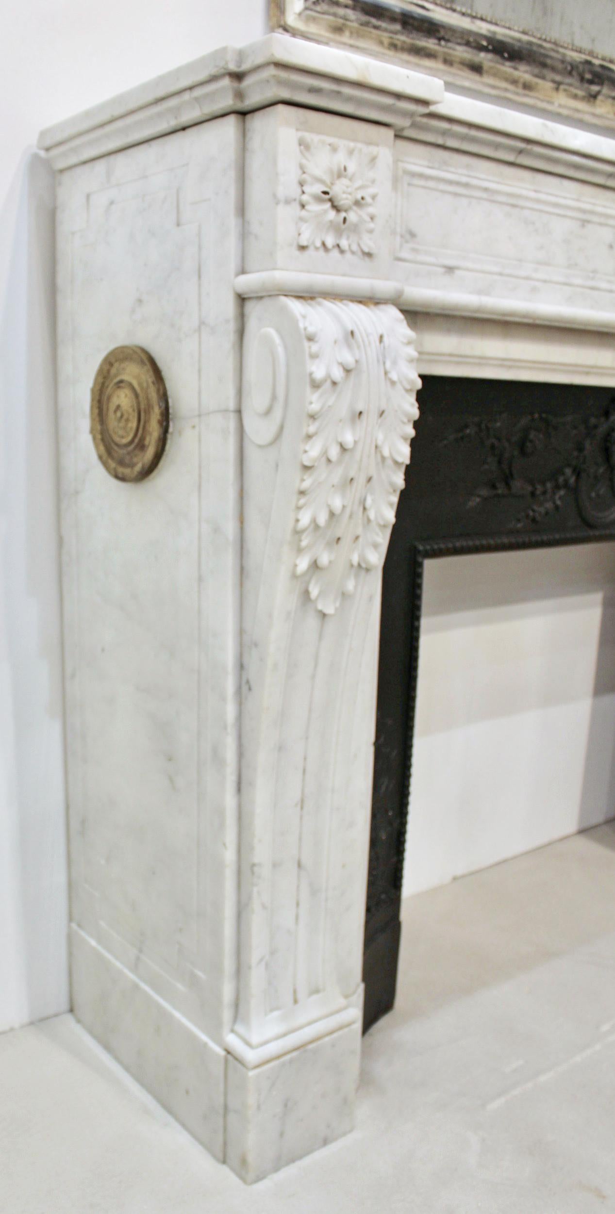 Louis XVI fireplace mantel in white hand carved Carrara marble, with decorative Bronze doré vents. Large carved Acanthus leaves are covering the top of the arched jambs resting on fluted console feet that sustain a bandeau ornated by sculpted square