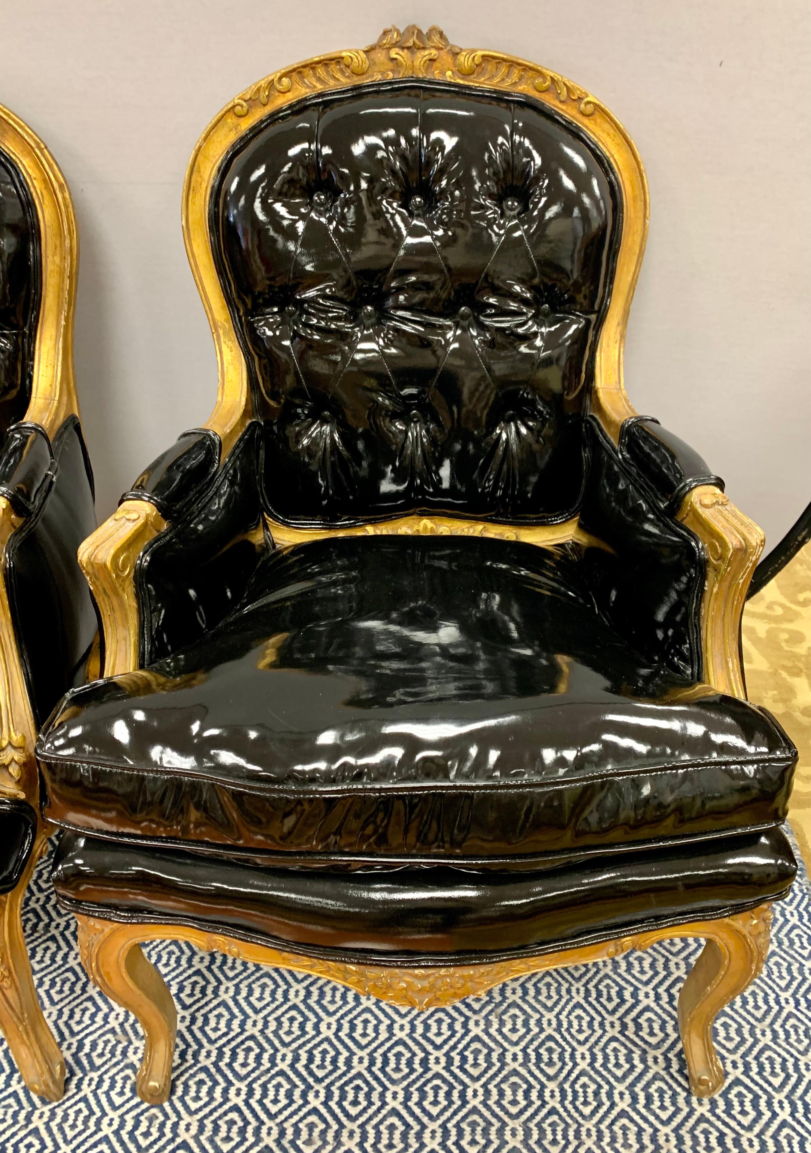 Pair of beautiful French bergeres with gilt frames and cabriole legs. Carved detail on the crest and legs. Tufted black faux patent leather upholstery.